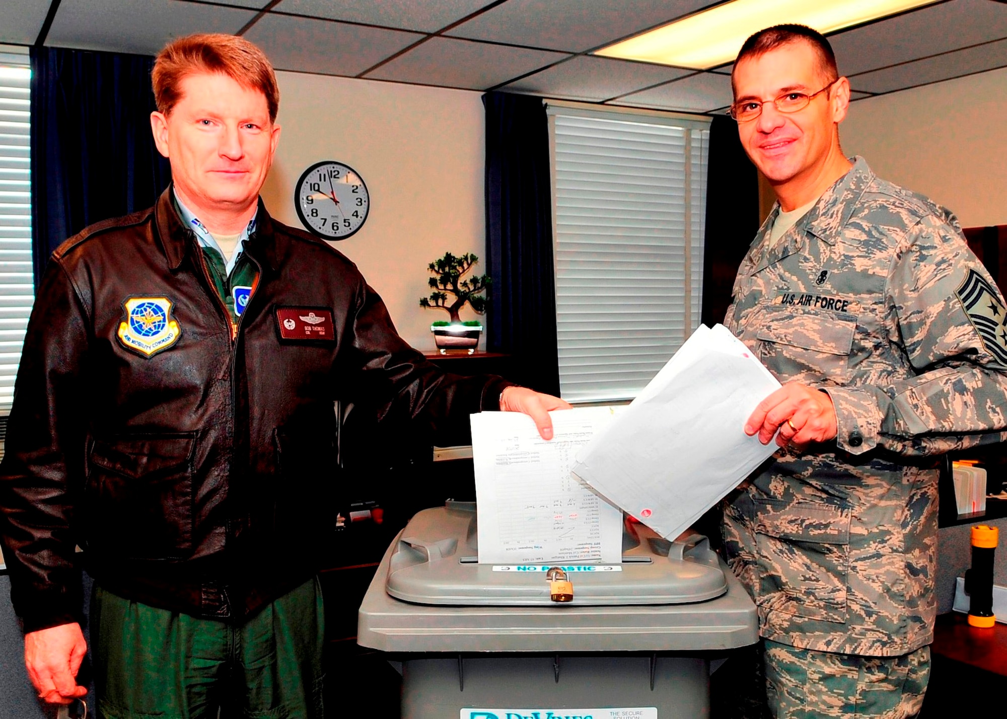 Col. Robert Thomas, 92nd Air Refueling Wing commander, and Chief Master Sgt. David Nordel, 92nd ARW command chief, toss paper into one of the 42 shredder bins deployed around base in support of the first day of Sort, Straighten, Shine, Standardize, Sustain and Safety program, also known as 6S, Feb. 3. After the Total Force Integration move, 6S was implemented as part of the base-wide clean up, providing an opportunity for units to rid their offices of clutter and free up needed space. (U.S. Air Force photo / Airman 1st Class Melissa L. Barnett)