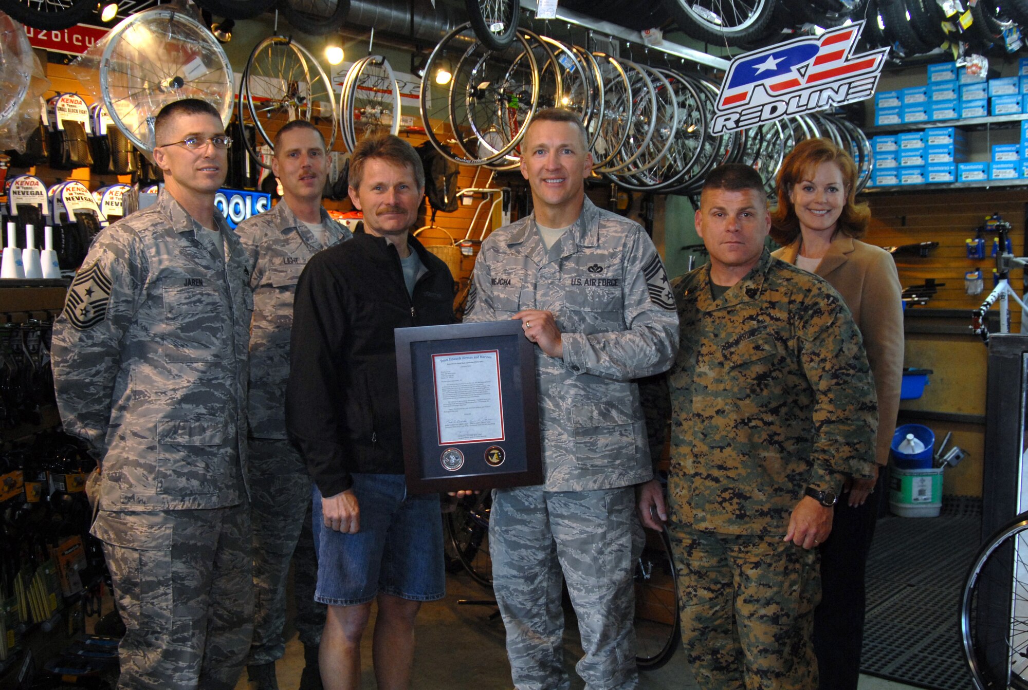 Chief Master Sgt. Mark Brejcha (third from right), 412th Test Wing command chief, presents a plaque of appreciation to Mike Grace (fourth from right), Bicycle John's manager, in Acton, Calif., Jan. 7. Bicycle John's ran a toy drive to donate all toys to the Edwards community for the Angel Tree and Toys for Tots. This is part of Team Edwards' thanksgiving to the local community that provided joy to military families during the holiday season.(Air Force photo by Senior Airman Julius Delos Reyes)