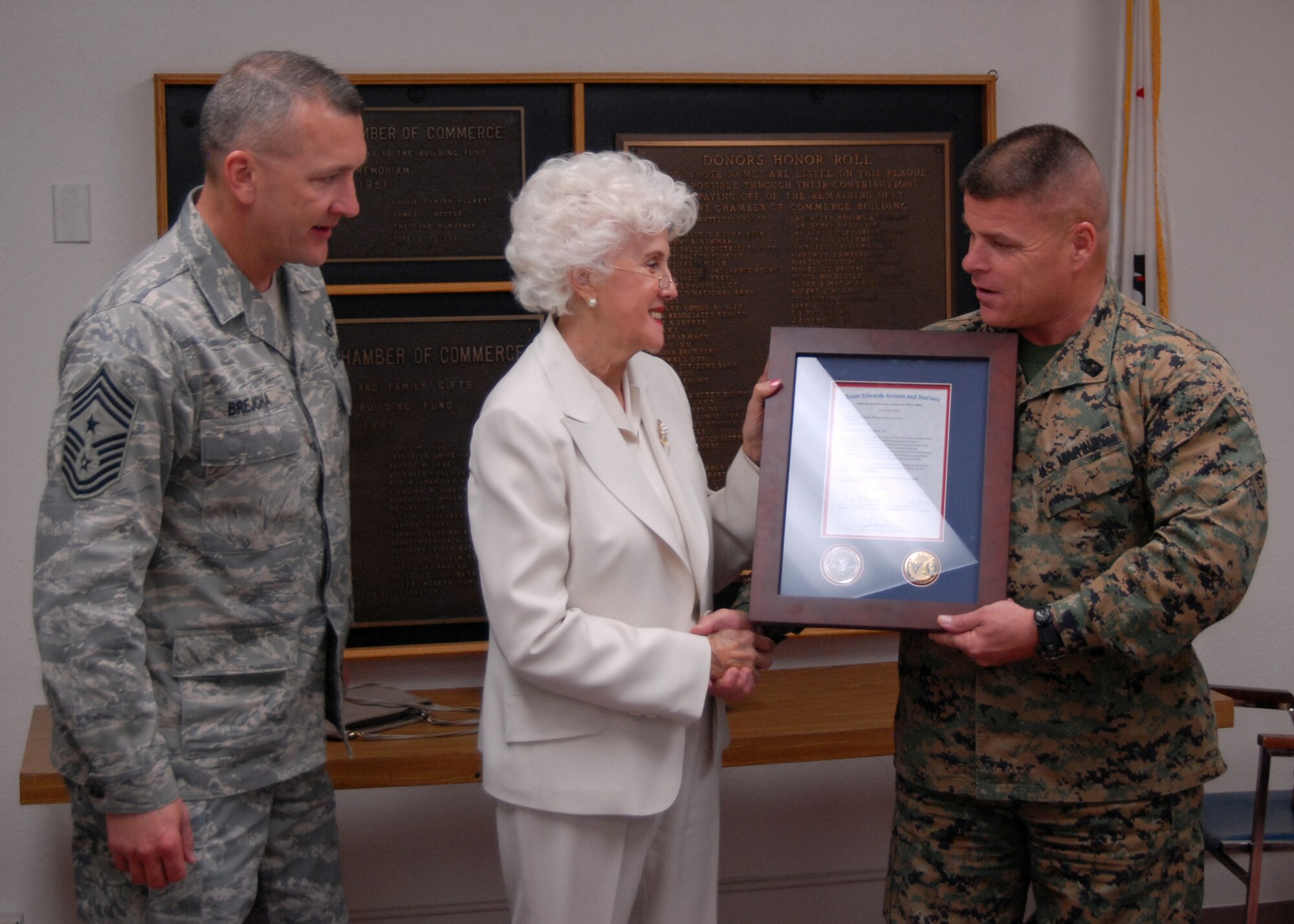Marine Sgt. Maj. Charles Dillree (right), Marine Aircraft Group 46 Detachment Bravo sergeant major, presents a plaque Jan. 8 to Aida O'Connor (center), Civilian Military Group president, as Chief Master Sgt. Mark Bejcha, 412th Test Wing command chief, looks on. This is part of Team Edwards' thanksgiving to local community that provided joy to military families during the holiday season. The Civ-Mil group donated to the Thanksgiving baskets for food vouchers for those servicemembers who needed a little extra help last year. (Air Force photo by Airman 1st Class William O'Brien)
