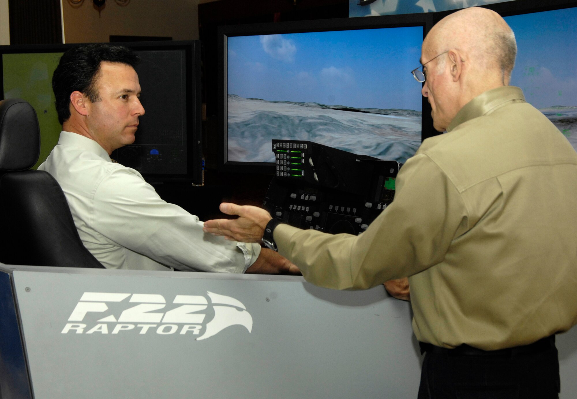WBZ-TV Channel 4 anchorman and 66th Air Base Wing honorary commander Jonathan Elias gets advice from Keith Bilyeu of the traveling F-22 Raptor demonstrator team while taking his 'test' flight Feb. 4.  The demonstrator, set up in the ballroom of Hanscom AFB's Minuteman Club Feb. 3-5, allows people to experience the thrills and challenges of flying the world’s most advanced fighter jet.