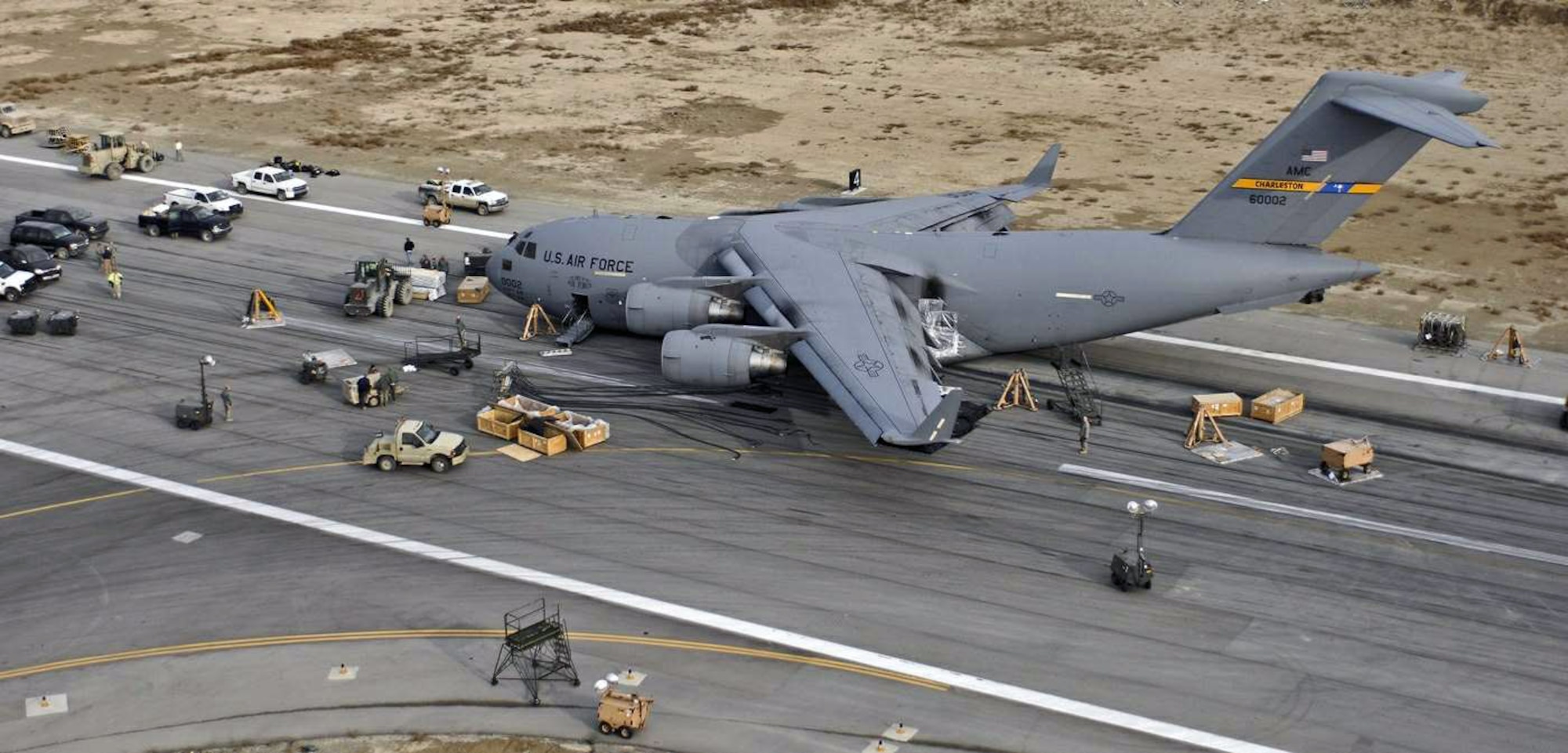 Crash recovery and emergency management crews survey a C-17 Globemaster III Jan. 31 as it rests on the active runway of Bagram Airfield, Afghanistan, after landing Jan. 30 with its landing gear retracted. More than 120 Airmen, Defense Department civilians and contractors successfully removed the crippled aircraft from the runway Feb. 2 and restored full airfield operations shortly thereafter. The "belly up," or no landing gear, recovery effort was the first in the airframe's 16-year Air Force history.  (U.S. Air Force photo/Senior Airman Erik Cardenas)