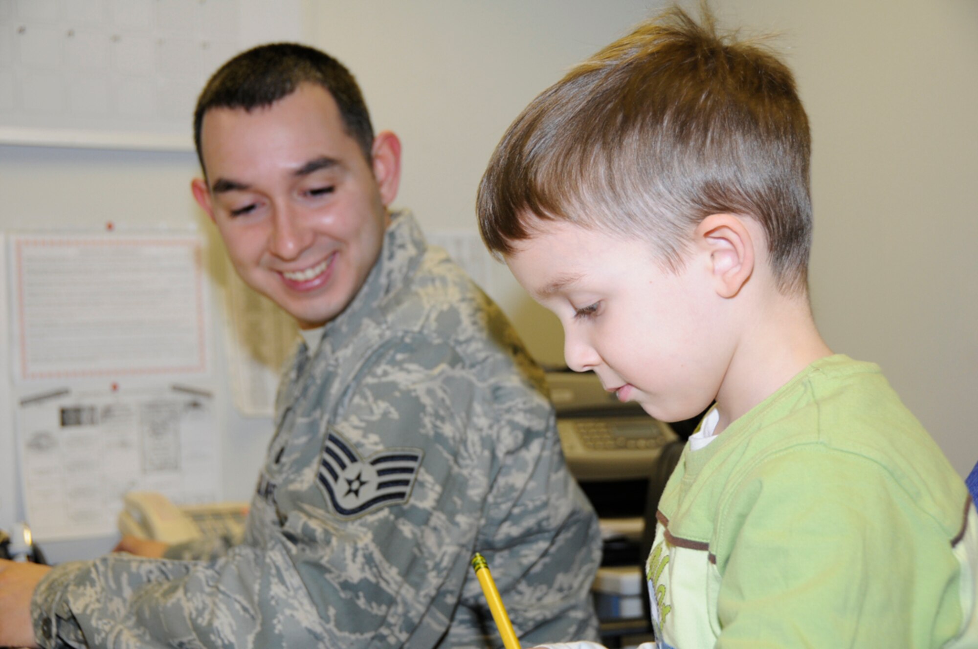 Five-year-old Dominick, son of Staff Sgt. Manny Rodriguez, 48th Security Forces Squadron individual newcomer treatment and orientation monitor, helps his dad prepare sponsorship packages Feb. 2 at RAF Lakenheath, England. Several children around the base had the opportunity to spend the day with their parents, while learning job skills, during a Job Shadow Day. (U.S. Air Force photo by Senior Airman Nicholas McNaughton)