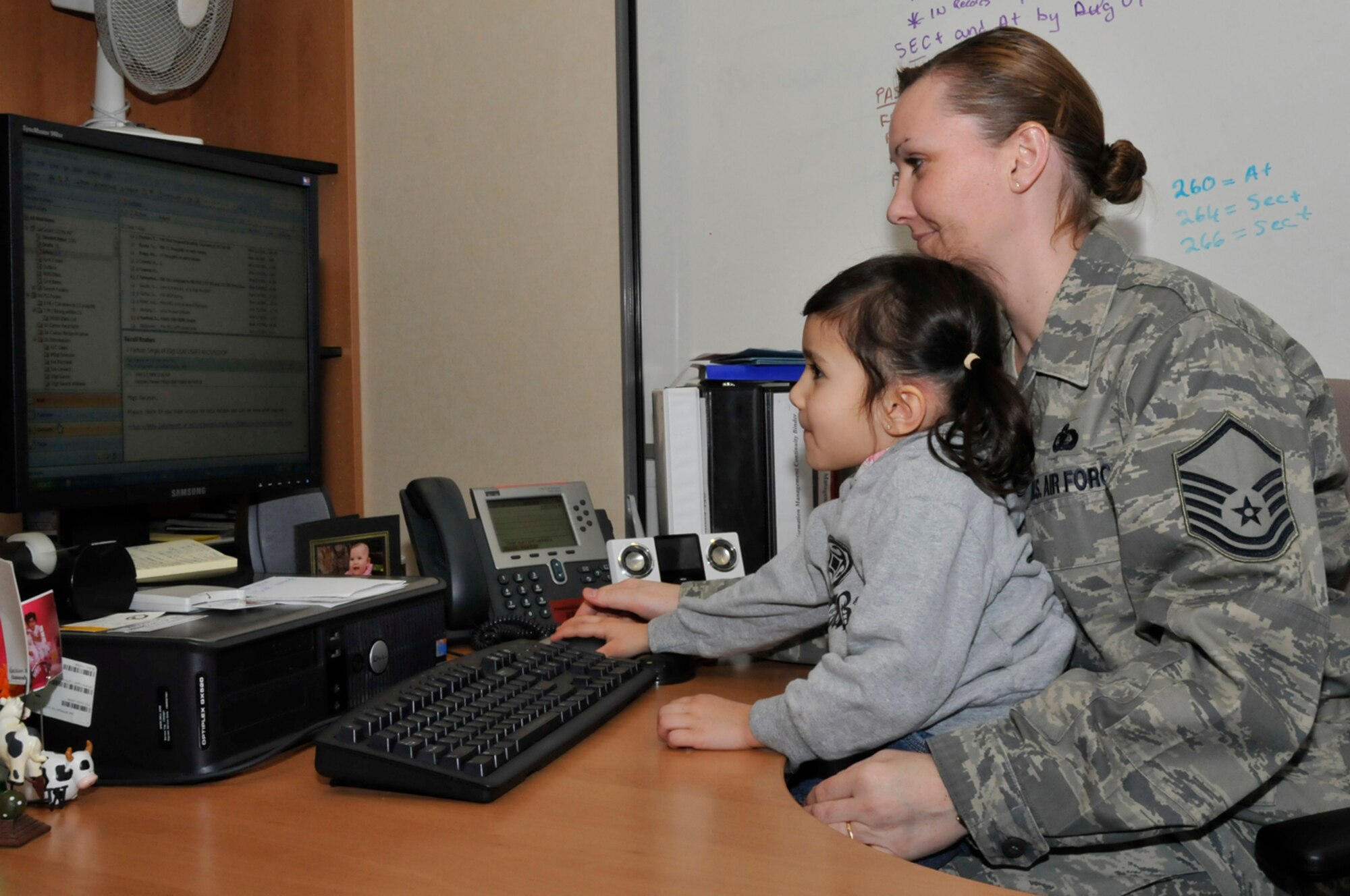 AisLinnJoy Gacayan helps her mother Master Sgt. Pamela Gacayan, 48th Communications Squadron, check email Feb. 2 at RAF Lakenheath, England. Children were able to get a good idea of what their parents do each day during Job Shadow Day. (U.S. Air Force photo by Airman 1st Class Perry Aston)