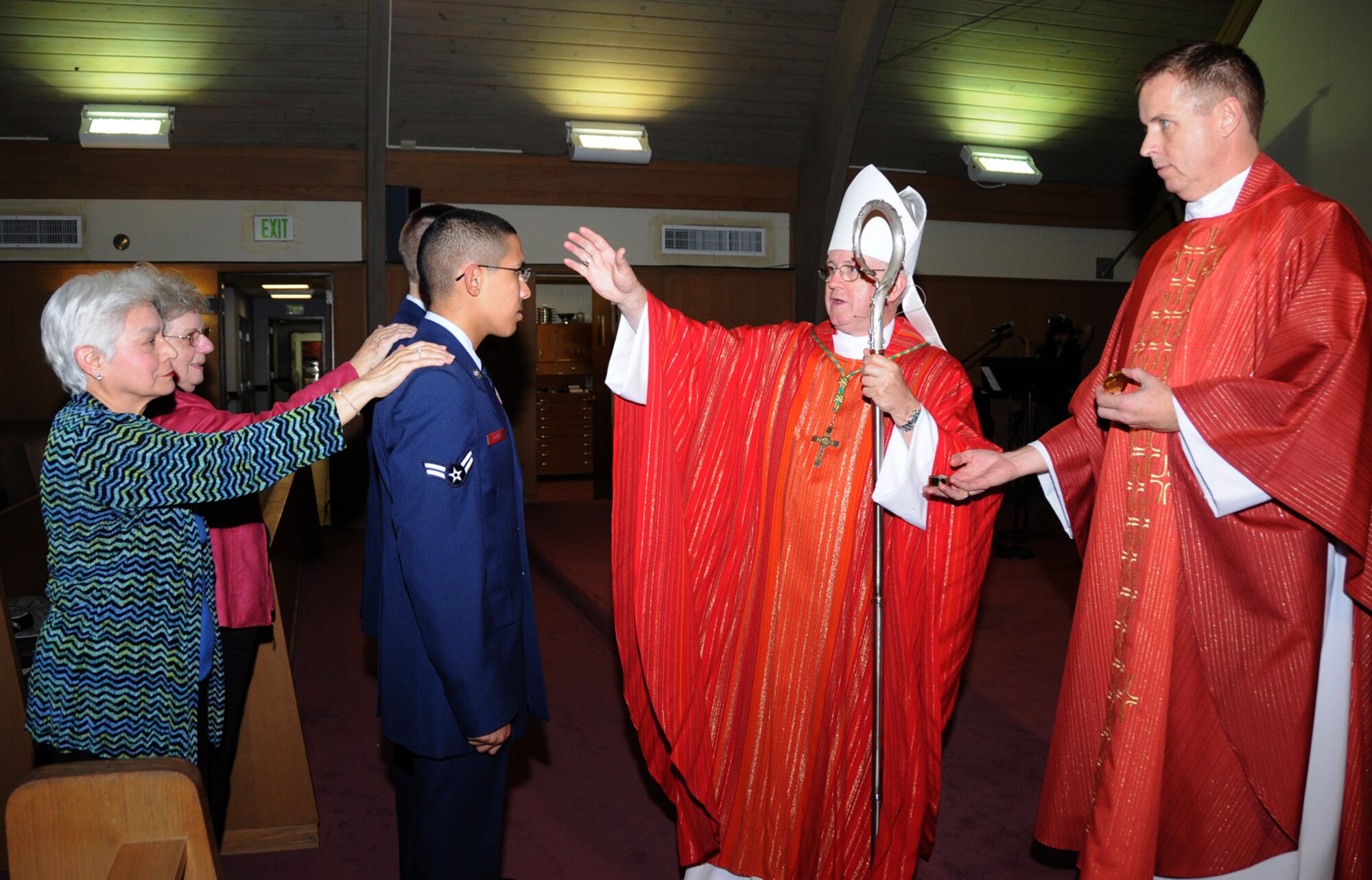 From left, sponsors Yorda Hay and Louise Turpel rest their hands on the shoulders of Airman 1st Class Miguel Alaniz and Airman James Inghram during a confirmation ceremony conducted by Bishop Richard Higgins, assisted by Keesler Chaplain (Lt. Col.) Francis Lowe.  Airman Alaniz is a student in the 332nd Training Squadron, and Airman Inghram is a student in the 334th TRS.  Bishop Higgins, a retired Air Force colonel who serves as auxiliary bishop of the Military Services Catholic Archdiocese, confirmed eight people at Keesler Jan. 28.  (U.S. Air Force photo by Kemberly Groue)
