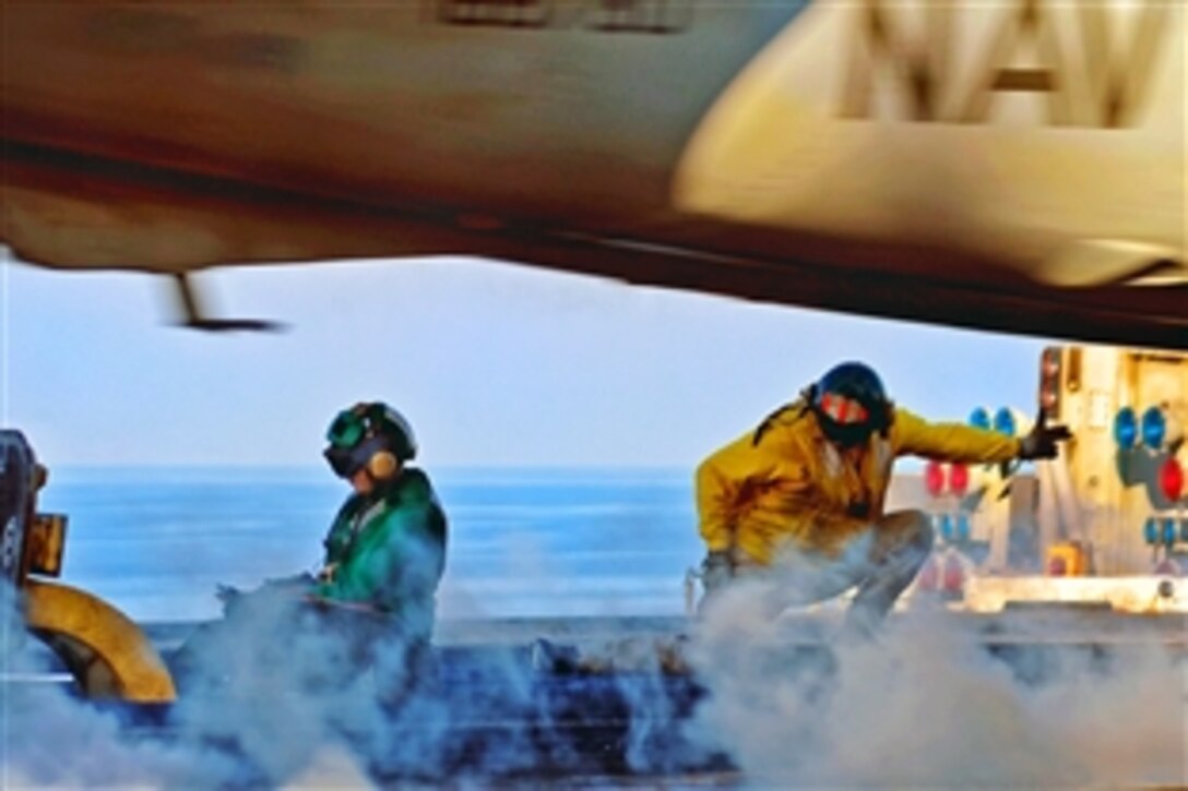 U.S. Navy Lt. Cmdr. Jason Pomponio, right, signals an aircraft to launch from the aircraft carrier USS Theodore Roosevelt in the Gulf of Oman, Jan. 31, 2009.