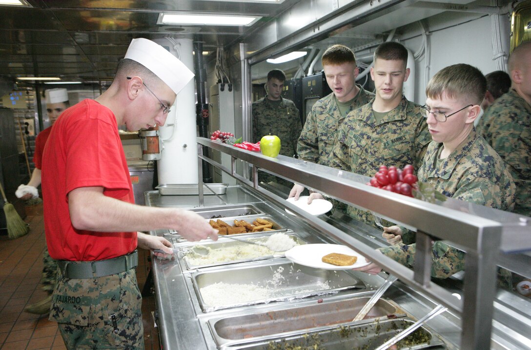 Lance Cpl. Mario Fajardo, from 22nd Marine Expeditionary Unit, serves chow in the galley aboard USS Bataan Feb. 4, 2009. Elements of the 22nd MEU are embarked aboard Bataan for Composite Training Unit Exercise. COMPTUEX is part of the MEU's pre-deployment training program. The 22nd MEU is scheduled to deploy this spring.::r::::n::(Official Marine Corps photo by Cpl. Theodore W. Ritchie)