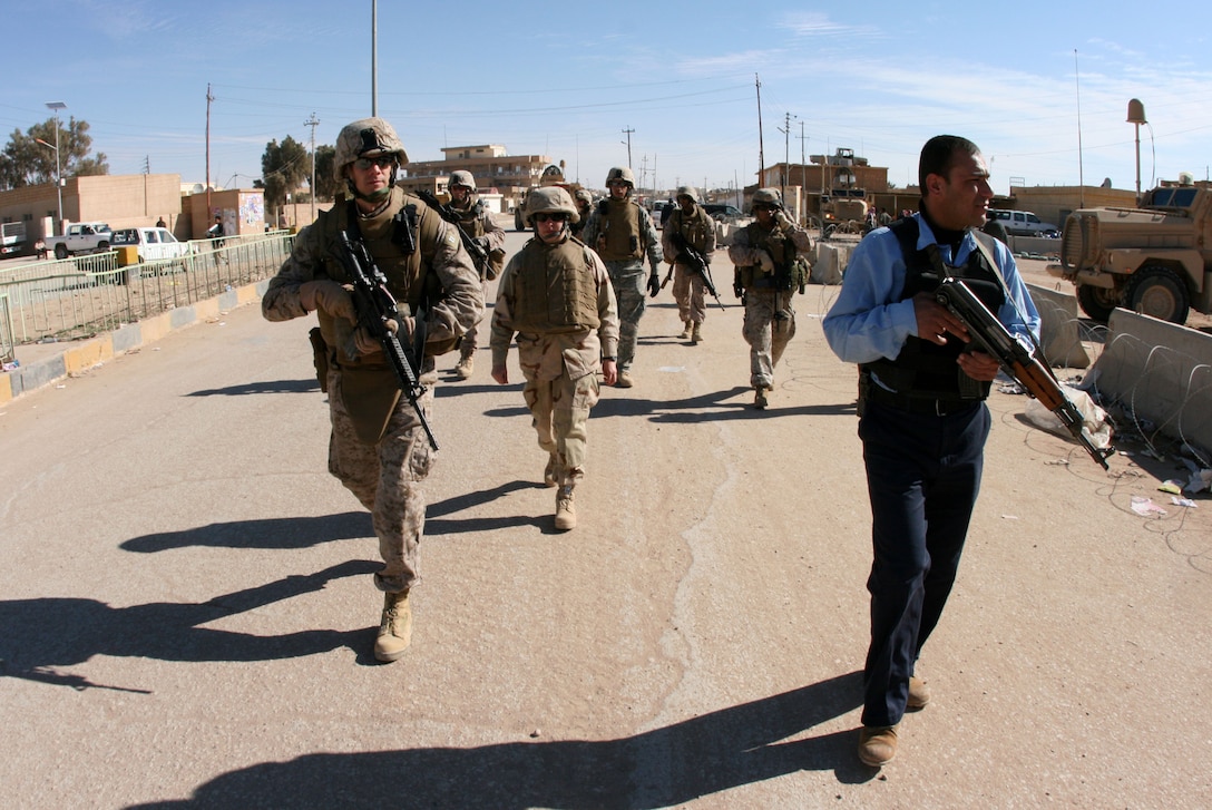 Capt. Justin Martell (front, left), the battalion judge advocate for 2nd Battalion, 25th Marine Regiment, Regimental Combat Team 8, and an Iraqi police officer make their way on a foot patrol to the courthouse in Rutbah, Iraq, Feb. 5.  For the past several months, Martell met almost weekly with an Iraqi judge to help successfully coordinate efforts of Coalition and Iraqi Security Forces in apprehending and prosecuting those suspected of insurgent activity. (Official USMC photo by Capt. Paul L. Greenberg)