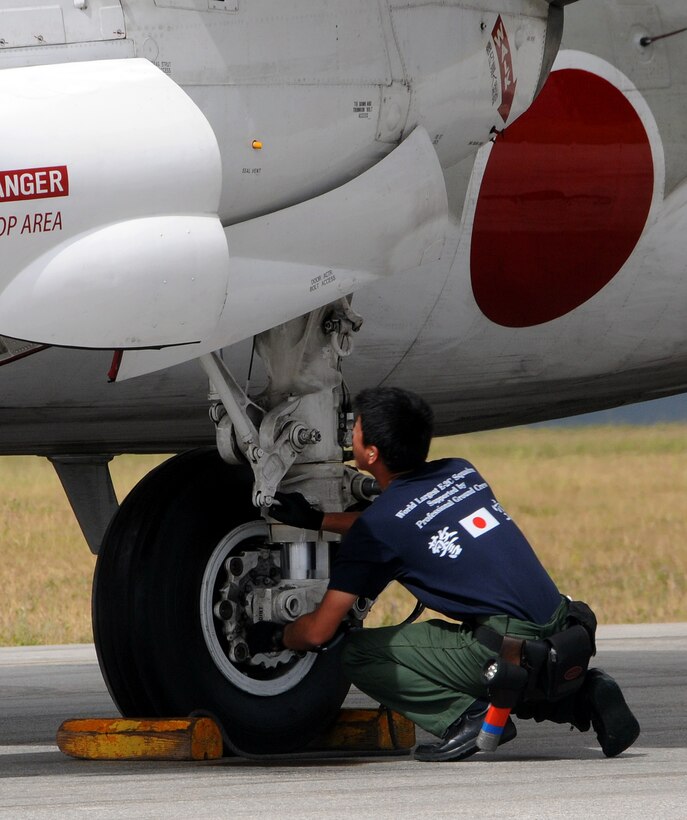 ANDERSEN AIR FORCE BASE, Guam - Japan Air Self Defense Force air crew member checks the wheel systems of an E-2C Hawkeye after landing here during an exercise for Cope North Feb. 5. The aircraft is operated by a crew of five, with the pilot and co-pilot on the flight deck and the combat information centre officer, air control officer and radar operator stations located in the rear fuselage directly beneath the rotodome. The E-2Cs are deployed to Guam  from the 601st Squadron, Misawa Air Base. (U.S. Air Force photo by Airman 1st Class Courtney Witt)(released)