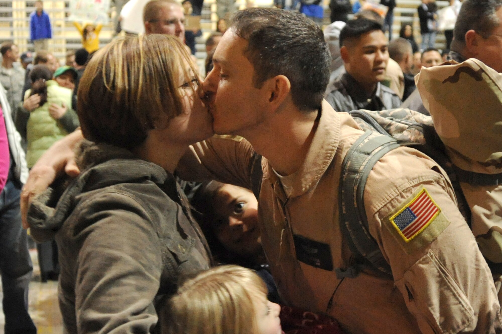 Tech. Sgt. Eric Newton kisses his wife, Tech. Sgt. Kristina Newton, while their children, Colin and Elizabeth, gather around during the Operation Homecoming ceremony at Eglin Air Force Base's King Hangar Feb. 4. Sergeant Newton and 150 other Hurlburt Airmen returned home from deployments to the Middle East. (U.S. Air Force photo/Senior Airman Stephanie Jacobs)