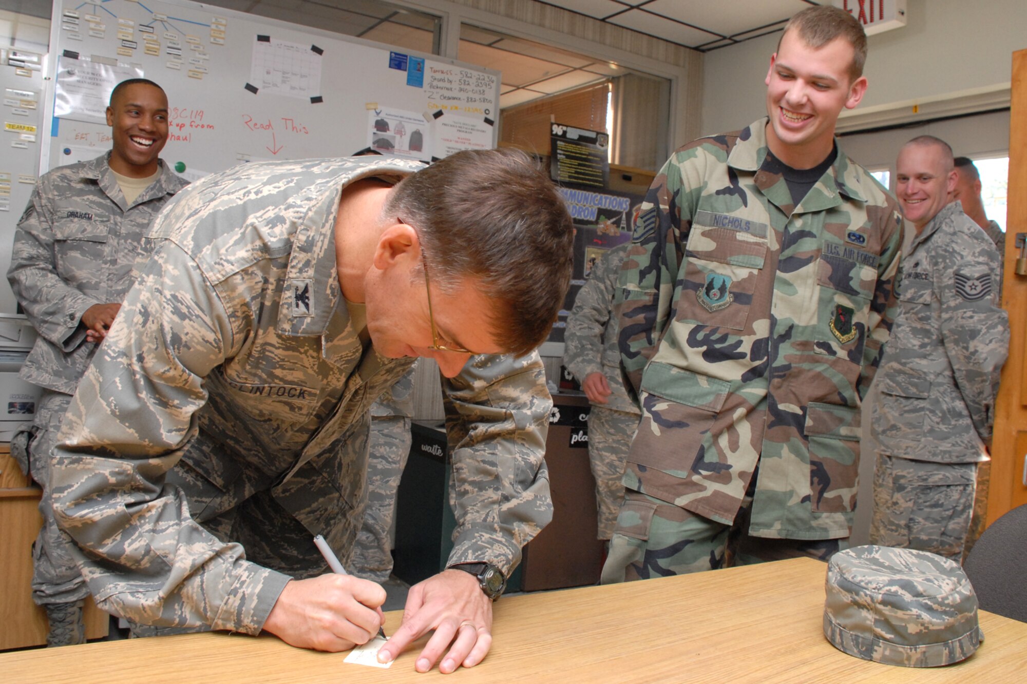 EGLIN AIR FORCE BASE, Fla. -- Col. Bruce McClintock, 96th Air Base Wing commander, signs a one-day pass for Staff Sgt. Timothy Nichols, 96th Communication Squadron cable and antenna systems, going above and beyond in his duties during a weekly walkabout Jan. 30. Airmen in the communications squadron install, maintain and repair cable and antenna services for all users across Eglin's 724 square miles. They also maintain $15M Local Area Network systems and tests completed LAN installations for compliance. Colonel McClintock and Chief Master Sgt. Troy Engholm, 96th ABW command chief master sergeant, take a weekly walkabout visit to the units on base to applaud their successes and determine their needs for mission accomplishment. (U.S. Air Force photo by Staff Sgt. Mike Meares)