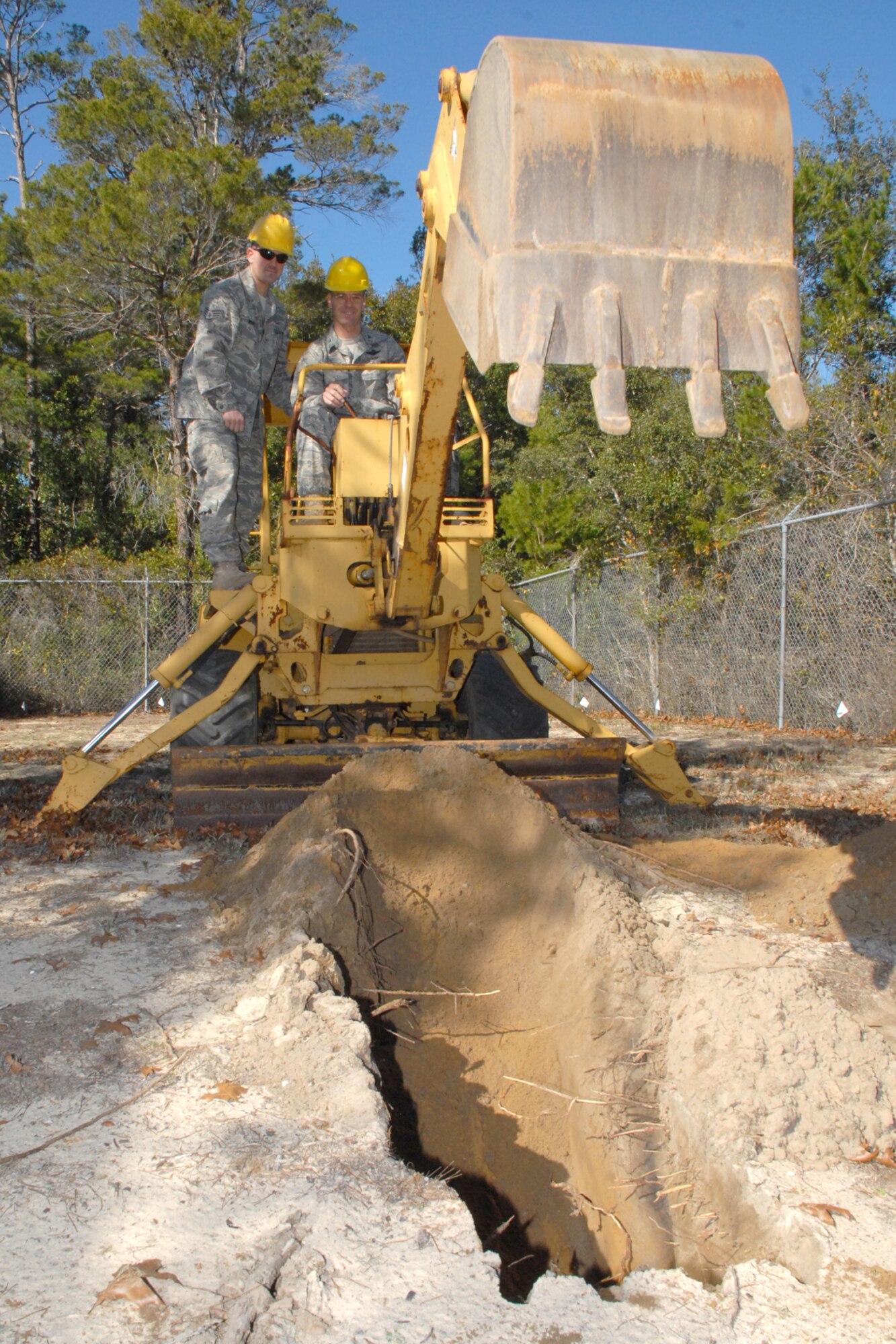 EGLIN AIR FORCE BASE, Fla. -- Col. Bruce McClintock, 96th Air Base Wing commander, gets hands-on instruction from Staff Sgt. Chris Wise, 96th Communication Squadron cable and antenna systems, on an excavator used to dig trenches. Sergeant Wise and the "Cable Dawgs" use the excavator to bury communications cable on Eglin. Airmen in the communications squadron install, maintain and repair cable and antenna services for all users across Eglin's 724 square miles. Colonel McClintock and Chief Master Sgt. Troy Engholm, 96th ABW command chief master sergeant, take a weekly walkabout visit to the units on base to applaud their successes and determine their needs for mission accomplishment. (U.S. Air Force photo by Staff Sgt. Mike Meares)