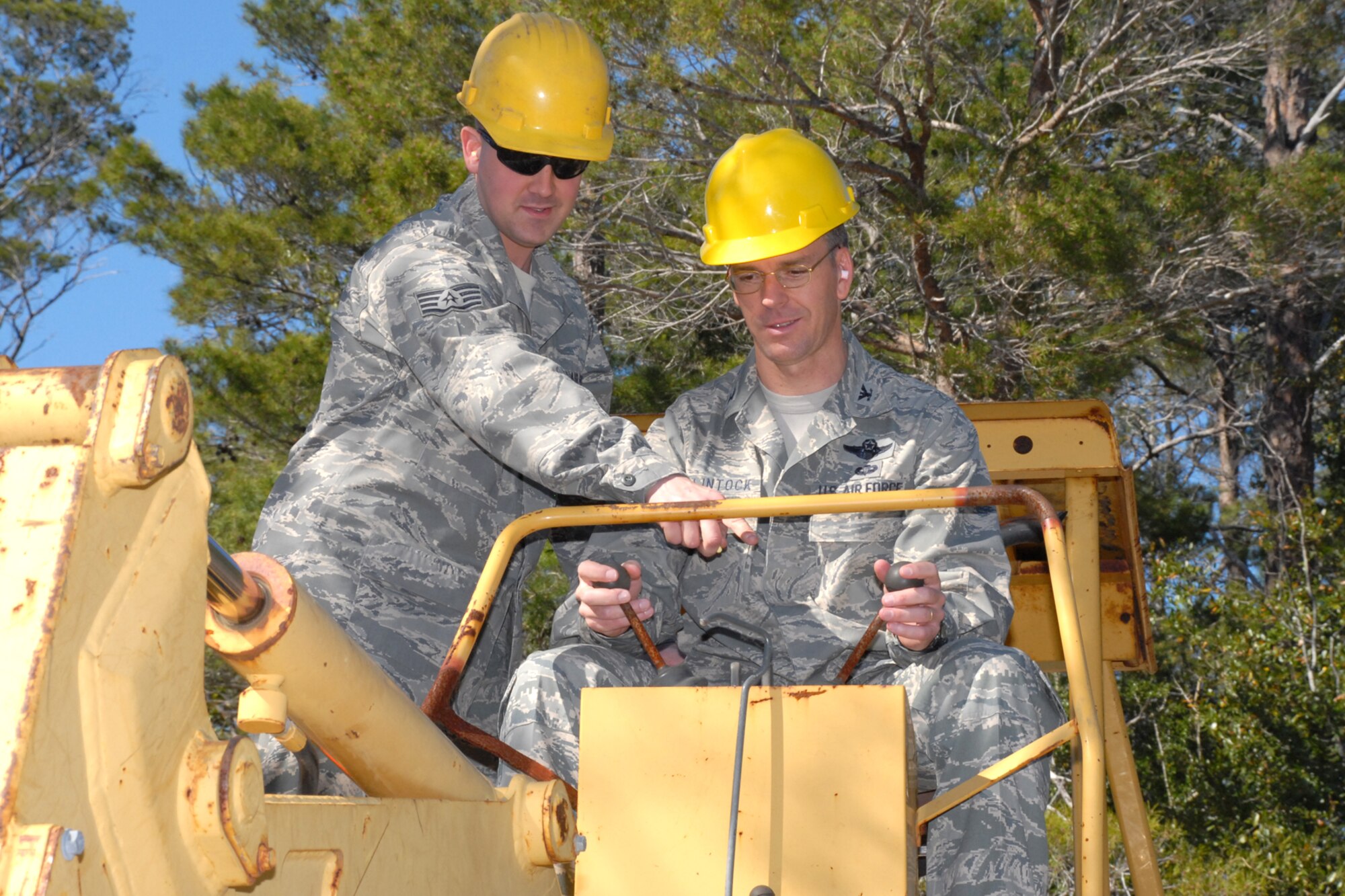 EGLIN AIR FORCE BASE, Fla. -- Col. Bruce McClintock, 96th Air Base Wing commander, gets hands-on instruction from Staff Sgt. Chris Wise, 96th Communication Squadron cable and antenna systems, on an excavator used to dig trenches. Sergeant Wise and the "Cable Dawgs" use the excavator to bury communications cable on Eglin. Airmen in the communications squadron install, maintain and repair cable and antenna services for all users across Eglin's 724 square miles. Colonel McClintock and Chief Master Sgt. Troy Engholm, 96th ABW command chief master sergeant, take a weekly walkabout visit to the units on base to applaud their successes and determine their needs for mission accomplishment. (U.S. Air Force photo by Staff Sgt. Mike Meares)