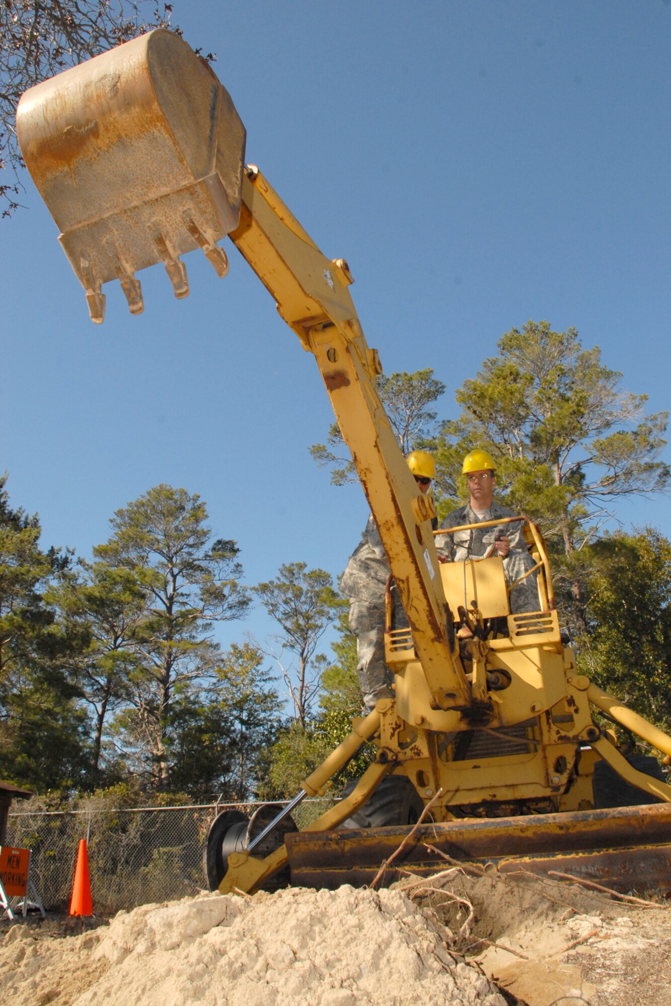 EGLIN AIR FORCE BASE, Fla. -- Col. Bruce McClintock, 96th Air Base Wing commander, gets hands-on instruction from Staff Sgt. Chris Wise, 96th Communication Squadron cable and antenna systems, on an excavator used to dig trenches. Sergeant Wise and the ?Cable Dawgs? use the excavator to bury communications cable on Eglin. Airmen in the communications squadron install, maintain and repair cable and antenna services for all users across Eglin's 724 square miles. Colonel McClintock and Chief Master Sgt. Troy Engholm, 96th ABW command chief master sergeant, take a weekly walkabout visit to the units on base to applaud their successes and determine their needs for mission accomplishment. (U.S. Air Force photo by Staff Sgt. Mike Meares)