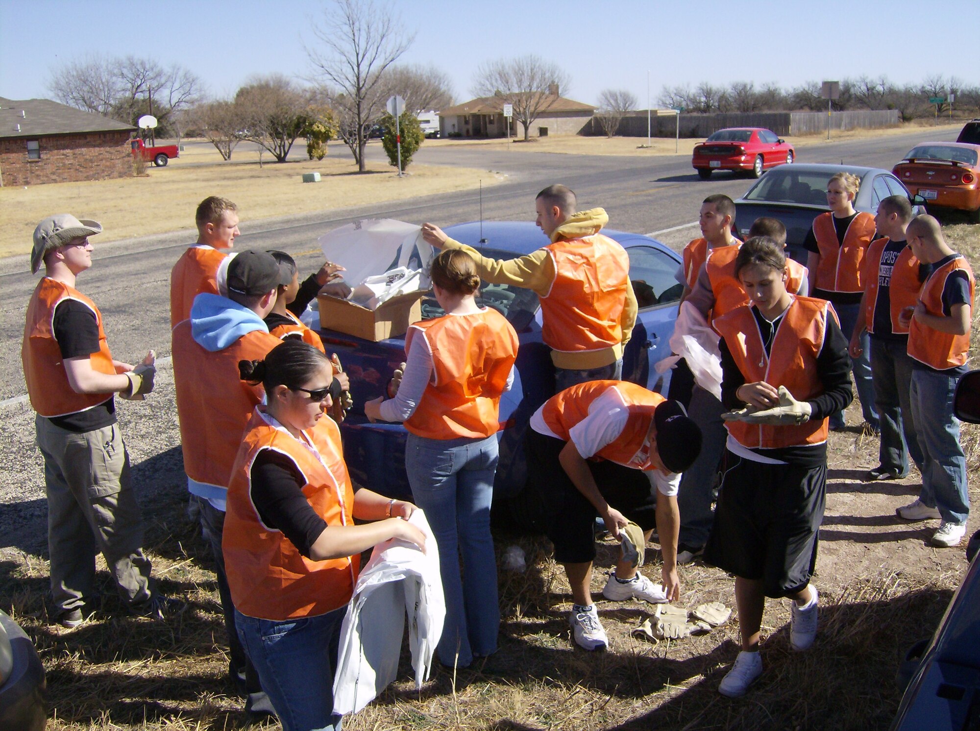 Members of the Armed Forces Committed to Excellence (ACE) don gloves and safety vests as they pick up trash bags for their Adopt-a-Highway cleanup Jan 30. (U.S. Air Force photo by Airman 1st Class Robert Fox-Stowe)