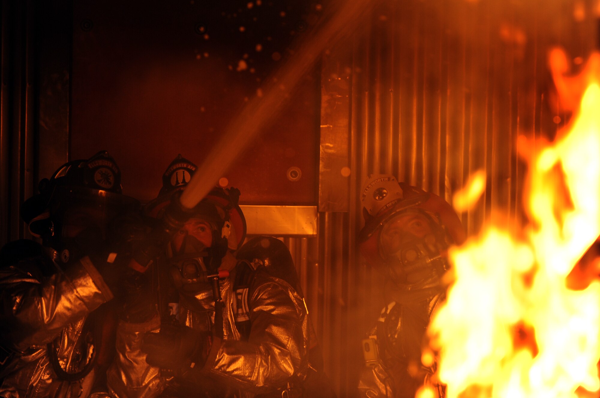 (Left to right) Airman 1st Class Christopher Levarek and Staff Sgt. Paul Rosato, 28th Civil Engineer Squadron fire protection specialists, spray water on a simulated structural fire while Aaron Wilke, 28 CES fire protection specialist, oversees the training exercise at here, Feb. 4. The 28 CES fire department conducts various training scenarios to maintain readiness qualifications. (U.S. Air Force photo/Airman 1st Class Joshua J. Seybert)
