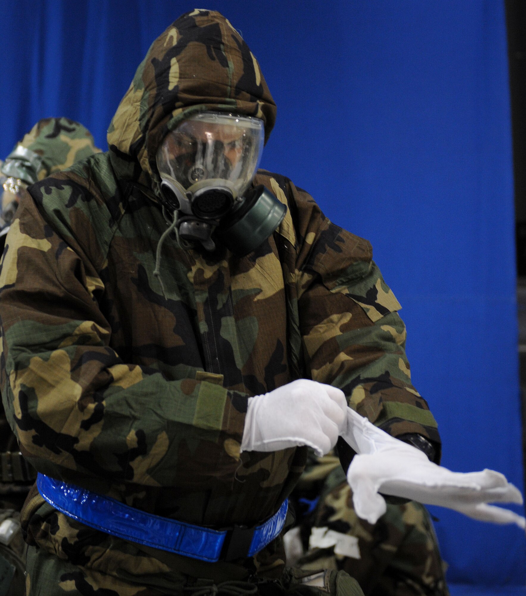 LANGLEY AIR FORCE BASE, Va. -- An Airman from the 1st Security Forces Squadron pulls his glove inserts on as he dresses in chemical warfare gear during an Ability to Survive and Operate Rodeo here Feb. 4. The rodeo provided training to more than 700 Airmen to prepare them for deployment.  (U.S. Air Force photo/Airman Rebecca Montez)