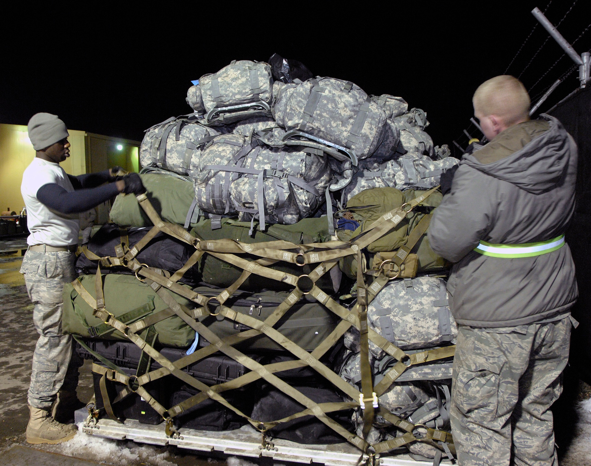 Airmen 1st Class Shaun Brown (left) and Jake Moennich palletize duffle bags, backpacks and other deployment gear to be airlifted U.S. forces members being deployed to Afghanistan Feb. 4 at Manas Air Base, Kyrgyzstan. Manas AB serves as a mobility hub for operations in Afghanistan, providing daily refueling missions and supporting personnel and cargo transiting in and out of Afghanistan. Airman Brown and Moennich are both with the 376th Expeditionary Logistics Readiness Squadron and are deployed from McConnell Air Force Base, Kan. (U.S. Air Force photo/Tech. Sgt. Phyllis Hanson) 
