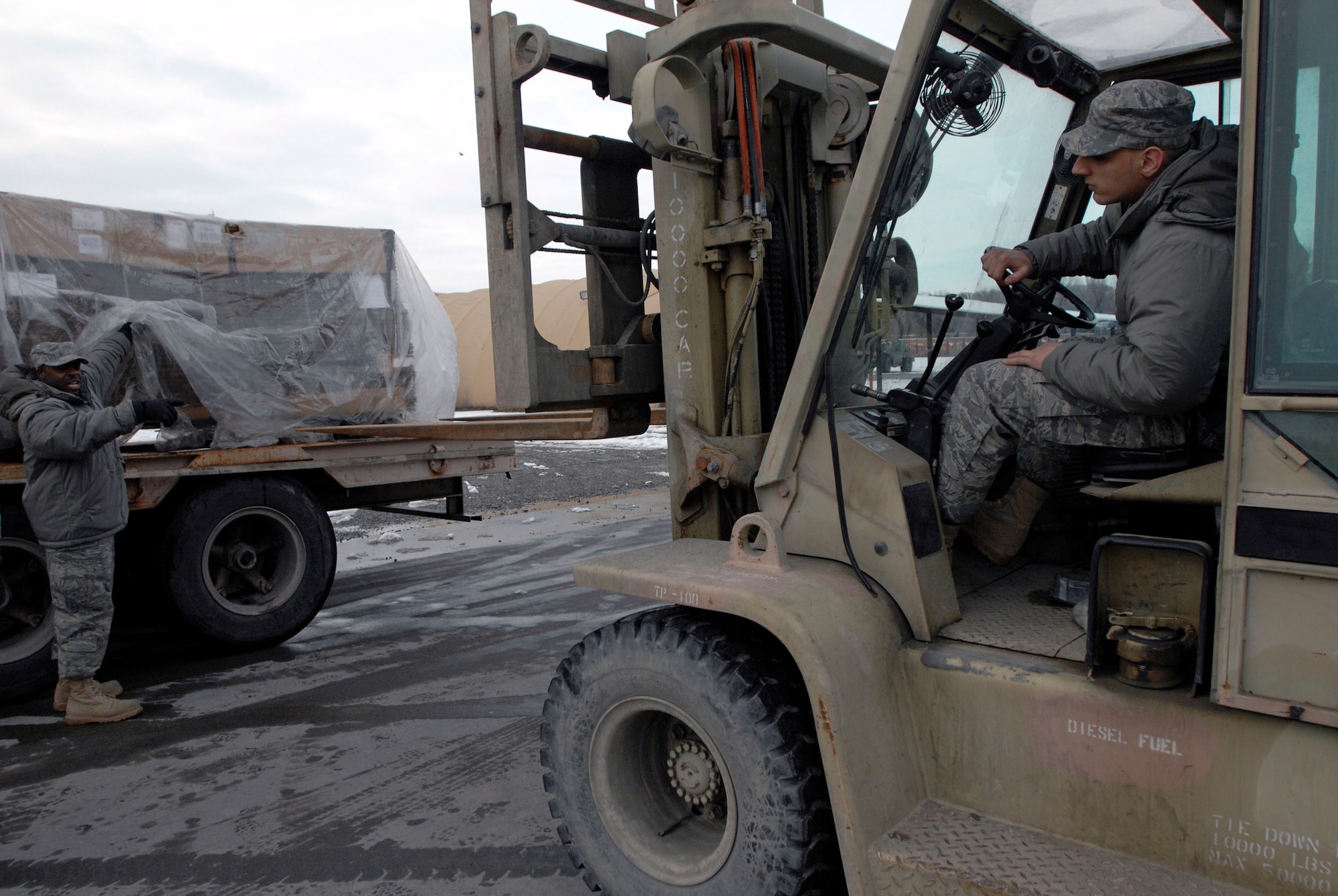 Senior Airman Taurence Campbell directs Airman 1st Class Brian Moeller to safely align the 10K forklift in order to offload a pallet of tri-wall boxes Feb. 4 at Manas Air Base, Kyrgyzstan. The boxes will be used for shipping military equipment to and from Afghanistan. Manas AB serves as a mobility hub for operations in Afghanistan, providing daily refueling missions and supporting personnel and cargo transiting in and out of Afghanistan. The Airmen are with the 376th Expeditionary Logistics Readiness Squadron here. Airman Campbell is deployed from McChord Air Force Base, Wash., and Airman Moeller is deployed from Ramstein AB, Germany. (U.S. Air Force photo/Tech. Sgt. Phyllis Hanson) 
