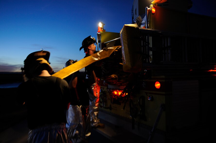 (Left to Right) Senior Airman Adam VanderZanden, 28th Civil Engineer operator, Airman 1st Class John Vasquez, 28th CES firefighter and William Cina, 28th CES operator, roll a hose into a fire truck during structural fire training here, Feb. 4. Simulated structural fires are conducted regularly to ensure Ellsworth firefighters maintain operational readiness and meet proper training requirements. (US Air Force photo/Airman 1st Class Corey Hook)