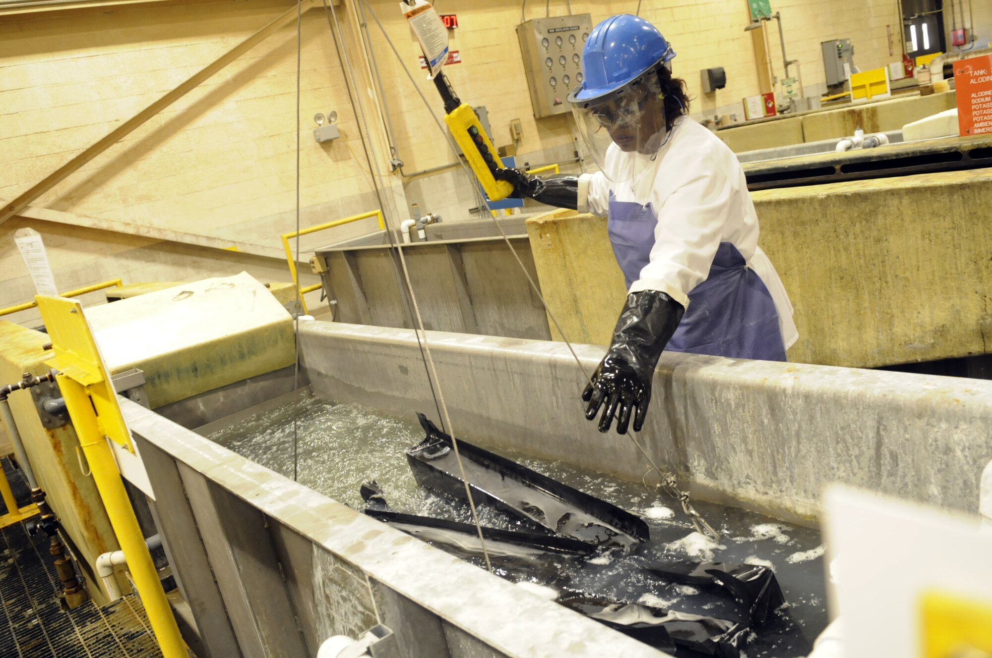Sarah Lane, electroplater, dips parts into a degreaser vat for cleaning. U. S. Air Force photo by Sue Sapp