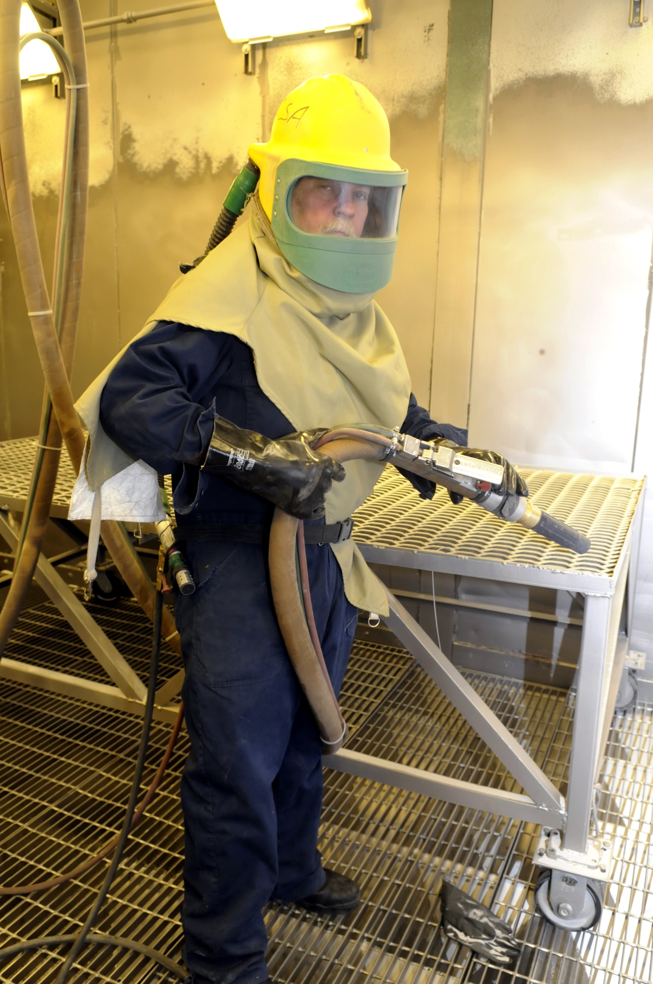 William Brown, electroplater, puts on a special helmet with air supply before going into a blasting booth. If the air supply to the worker is not good, a blue light and loud alarm sounds as a warning. U. S. Air Force photo by Sue Sapp