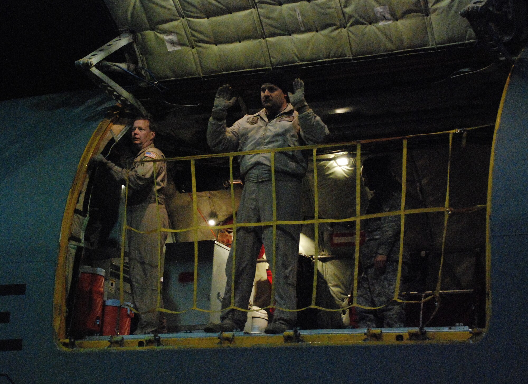 Tech. Sgt. Warren "Bear" Bearup communicates with flightline personnel at Bagram Air Field, Afghanistan, from a KC-135 Stratotanker cargo door. He was one of eight Reservists from the 931st Air Refueling Group to volunteer for a 12-day aeromedical evacuation mission that involved four trips in and out of Afghanistan. To his left is Master Sgt. Darren Demel, the only member of the crew to volunteer for one of the 931st's previous Afghanistan missions. Both sergeants are boom operators assigned to the 18th Air Refueling Squadron, the flying unit of the 931st. (Courtesy  photo)