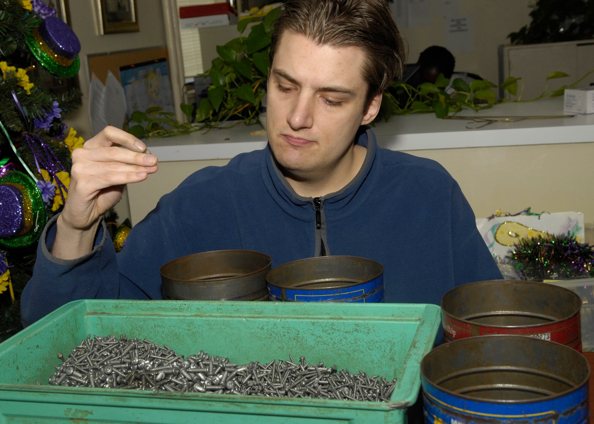 A client seperates nuts and bolts into various cans at the HAP house. (Senior Airman Alexandra M. Sandoval/U.S. Air Force)