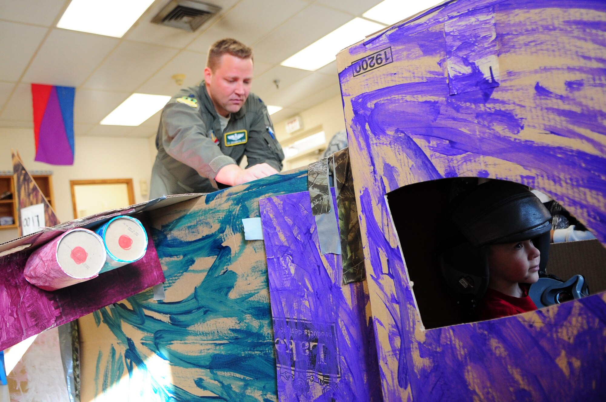 Lt. Col. Tyrell Chamberlain, father of Tyler, helps construct the nine-foot cardboard B-52 Stratofortress. (Senior Airman Joanna M. Kresge/U.S. Air Force)