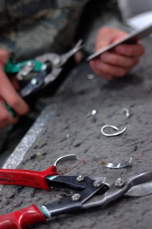 Airman 1st Class Adam Gibson snips pieces of sheet metal  inside the 437th Maintenance Squadron Aircraft Structural Maintenance Shop Feb. 4 to form a landing gear clip that will later be used to repair a C-17.The 437 MXS Aircraft Structural Maintenance Shop performs all structural maintenance and corrosion control for all C-17s assigned to the base.  Airman Gibson is an aircraft structural journeyman with the 315th Maintenance Squadron. (U.S. Air Force photo/Senior Airman Timothy Taylor) 