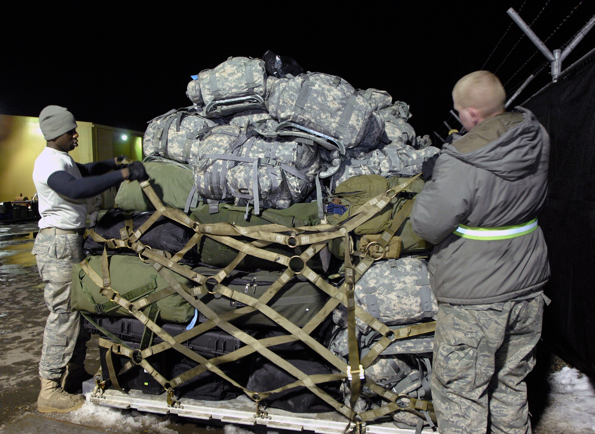 Airmen 1st Class Shaun Brown (left) and Jake Moennich palletize duffle bags, backpacks and other deployment gear, at Manas Air Base, Kyrgyzstan, Feb. 4, to be airlifted to Afghanistan for U.S. forces members being deployed to that region. Manas serves as a premier mobility hub for operations in Afghanistan, providing daily refueling missions and supporting personnel and cargo transiting in and out of Afghanistan. Airman Brown and Moennich are both with the 376th Expeditionary Logistics Readiness Squadron and are deployed from the 62nd Aerial Port Squadron at McConnell Air Force Base, Kansas. (U.S. Air Force photo/Tech. Sgt. Phyllis Hanson)