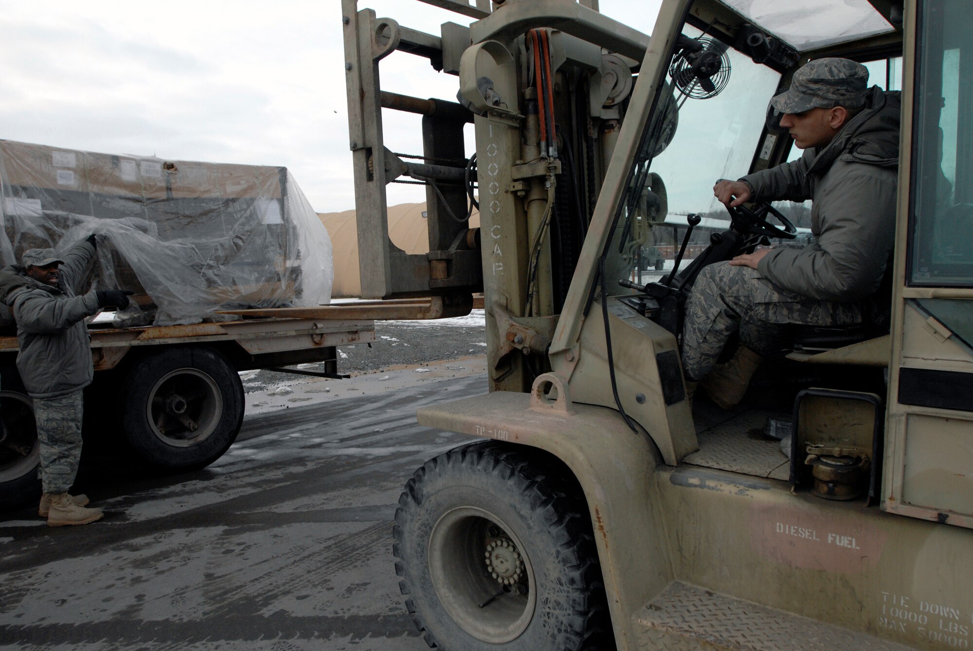 Senior Airman Taurence Campbell directs Airman 1st Class Brian Moeller to safely align the 10K forklift in order to offload a pallet of tri-wall boxes at Manas Air Base, Kyrgyzstan, Feb. 4. The boxes will be used for shipping military equipment to and from Afghanistan. Manas serves as a premier mobility hub for operations in Afghanistan, providing daily refueling missions and supporting personnel and cargo transiting in and out of Afghanistan. The Airmen are with the 376th Expeditionary Logistics Readiness Squadron here. Airman Campbell is deployed from the 62nd LRS at McChord Air Force Base, Wash., and Airman Moeller is deployed from the 435th LRS at Ramstein AB, Germany. (U.S. Air Force photo/Tech. Sgt. Phyllis Hanson)