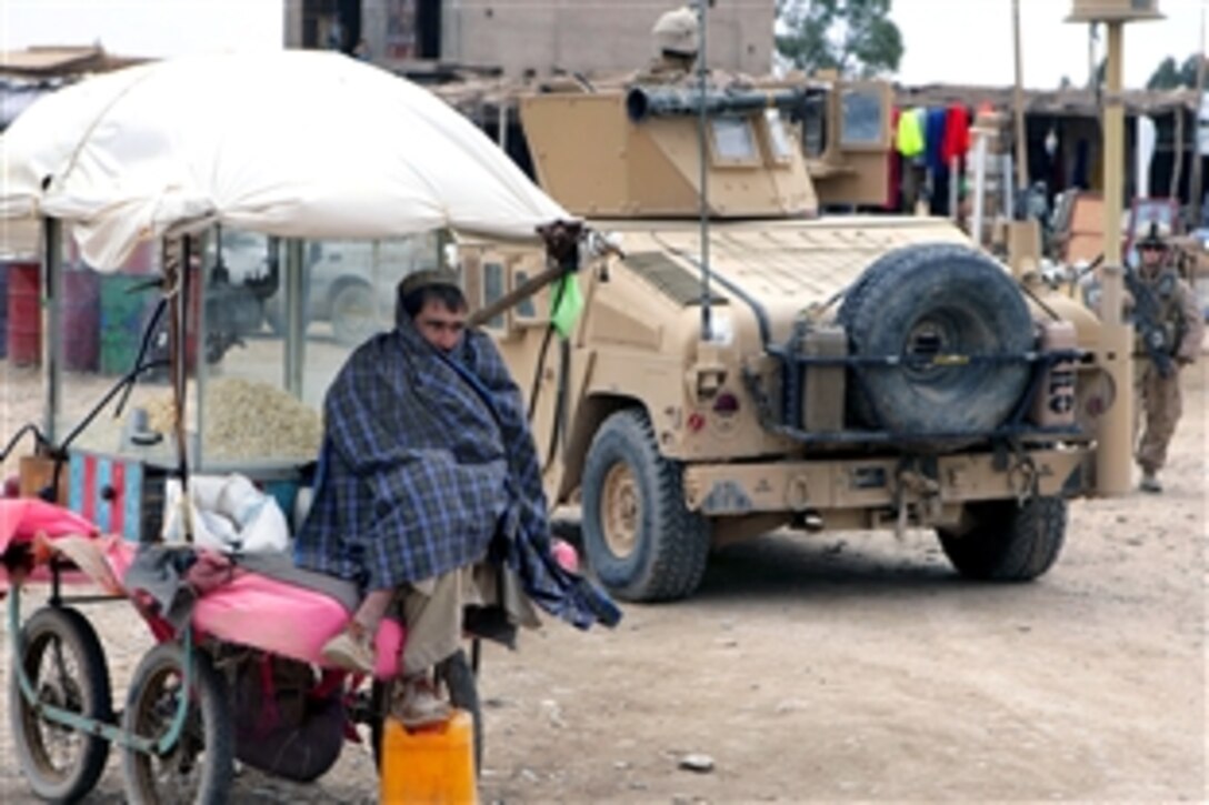 An Afghan watches as U.S. Marines and Afghan national police conduct a patrol through a local bazaar in Farah province, Afghanistan, Jan. 24, 2009. The Marines are assigned to Kilo Company, 3rd Battalion, 8th Marine Regiment, which is the ground combat element of Special Purpose Marine Air Ground Task Force - Afghanistan.