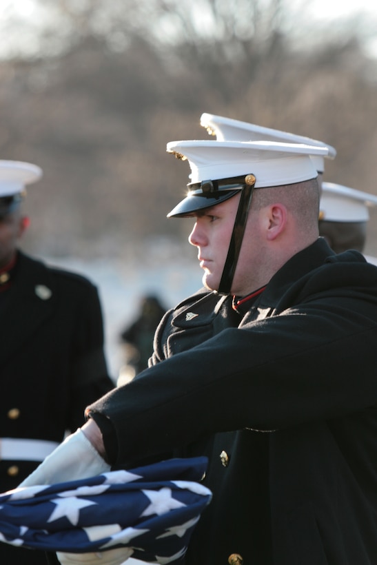 Cpl. Jason Darby, Marine Barracks Washington, passes the flag for the family of a fallen warrior during a funeral service at Arlington National Cemetery in Arlington, Va., Feb. 5. Lance Cpl. Julian T. Brennan was killed in action Jan. 24 as a result of injuries after being struck by an improvised explosive device while conducting combat operations in Farah Province, Afghanistan. Brennan is the first enlisted Marine to receive a full honors funeral under new CMC policy.
