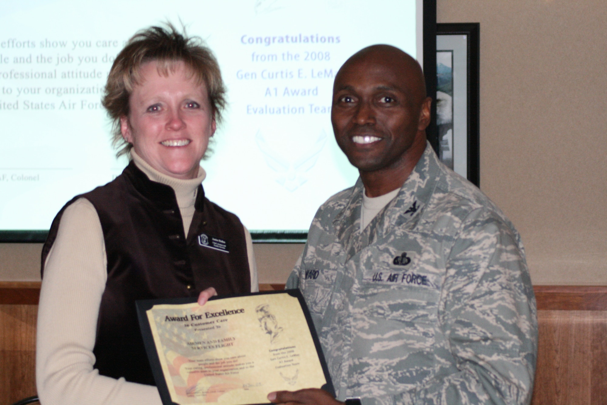 Janice hollen, Airman and Family Readiness Flight chief, accepts an Award for excellence in Customer Care on behalf of her flight from Col. Benjamin Ward, LeMay Team chief, during the LeMay team's departing ceremony Jan. 30 at Hill Air Force Base.