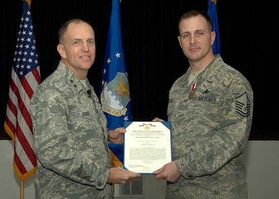 Maj. Gen. Ralph Jodice, Air Force District of Washington Commander, presents the Meritorious Service Medal and accompanying citation to Master Sgt. Charles L. Mercurio IV during the AFDW Commander's Call held at the Andrews Air Force Base, Md., Community Center Feb. 6. Sergeant Mercurio earned the medal for his service with the Air Force Honor Guard from July 2004 to December 2008.