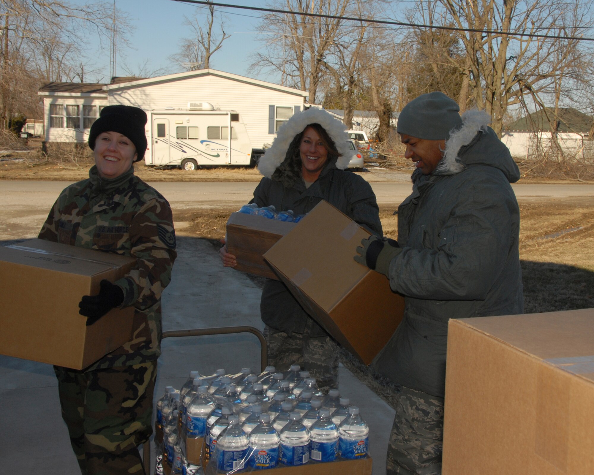 Kentucky Air National Guard members, TSgt. Monique Yuill, TSgt. Gene Jones and A1C Windy Wagner, gather meal kits and bottled water to distribute to needy residents of Bandana, Kentucky during ice storm relief efforts.
