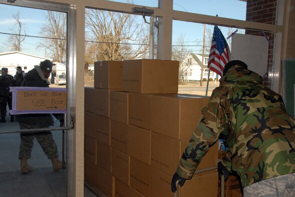 Two Airmen from the Kentucky Air National Guard, 123rd AW, move supplies outside to distribute to needy residents in Bandana, Kentucky for ice storm relief efforts.