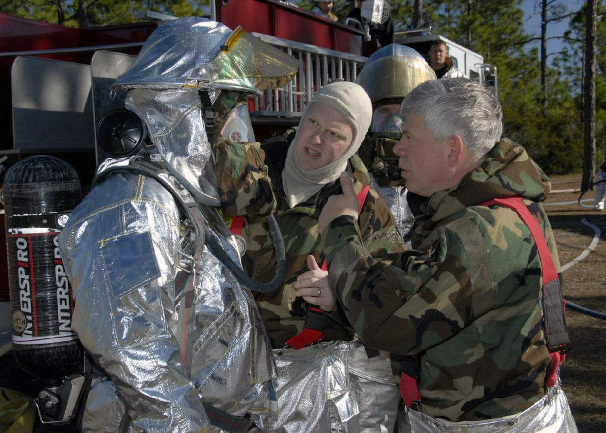 Chief Master Sgt. Armand Lamour (right) and Master Sgt. Travis Raby (center) assist another firefighter with his fire suit prior to firefighter training conducted during a Silver Flag exercise Feb. 3. Silver Flag exercise is an annual training exercise conducted at Tyndall Air Force Base, Fla., to train military personnel within their perspective career field. (U.S. Air Force photo/Senior Master Sgt. Robert J. Sabonis) 
