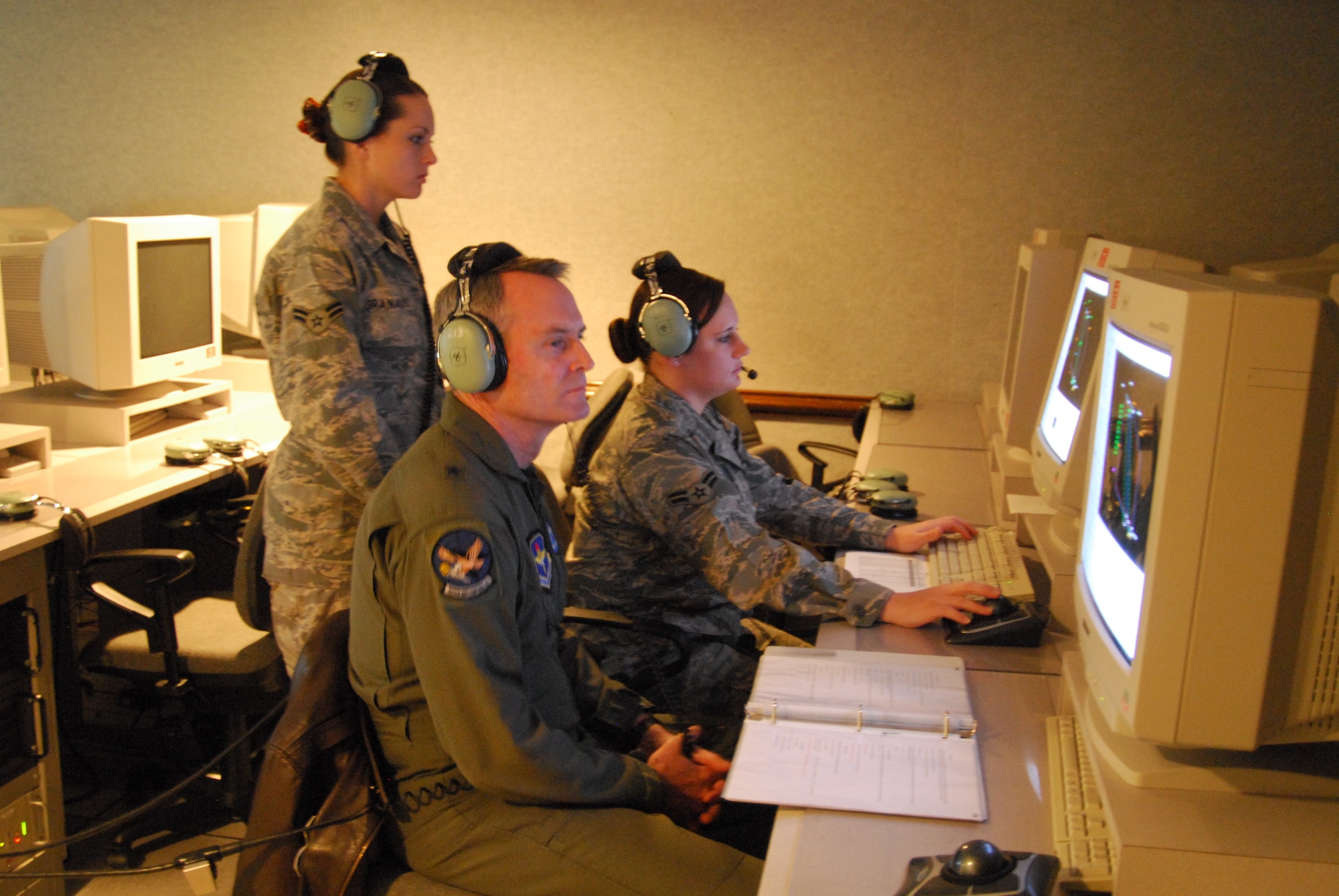 Airman 1st Class Genny Taylor, 325th Air Control Squadron pilot simulator, and Airman 1st Class Angela Granados, 325th ACS pilot simulator, demonstrate their duties to Brig. Gen. Darryl Roberson, 325th Fighter Wing commander.  Airman Taylor, selected for the Commander’s Shadow Program, is responsible for supporting training for more than 165 officer students annually.  “(Airman 1st Class Genny Taylor bleeds Air Force blue and is truly tops amongst her peers,” said Staff Sgt. Quincy Moore, Airman Taylor’s supervisor and nominator.  Serving in the Air Force for a year and a half, Airman Taylor hails from Fremont, Neb.  (U.S. Air Force photo by Lisa Norman)