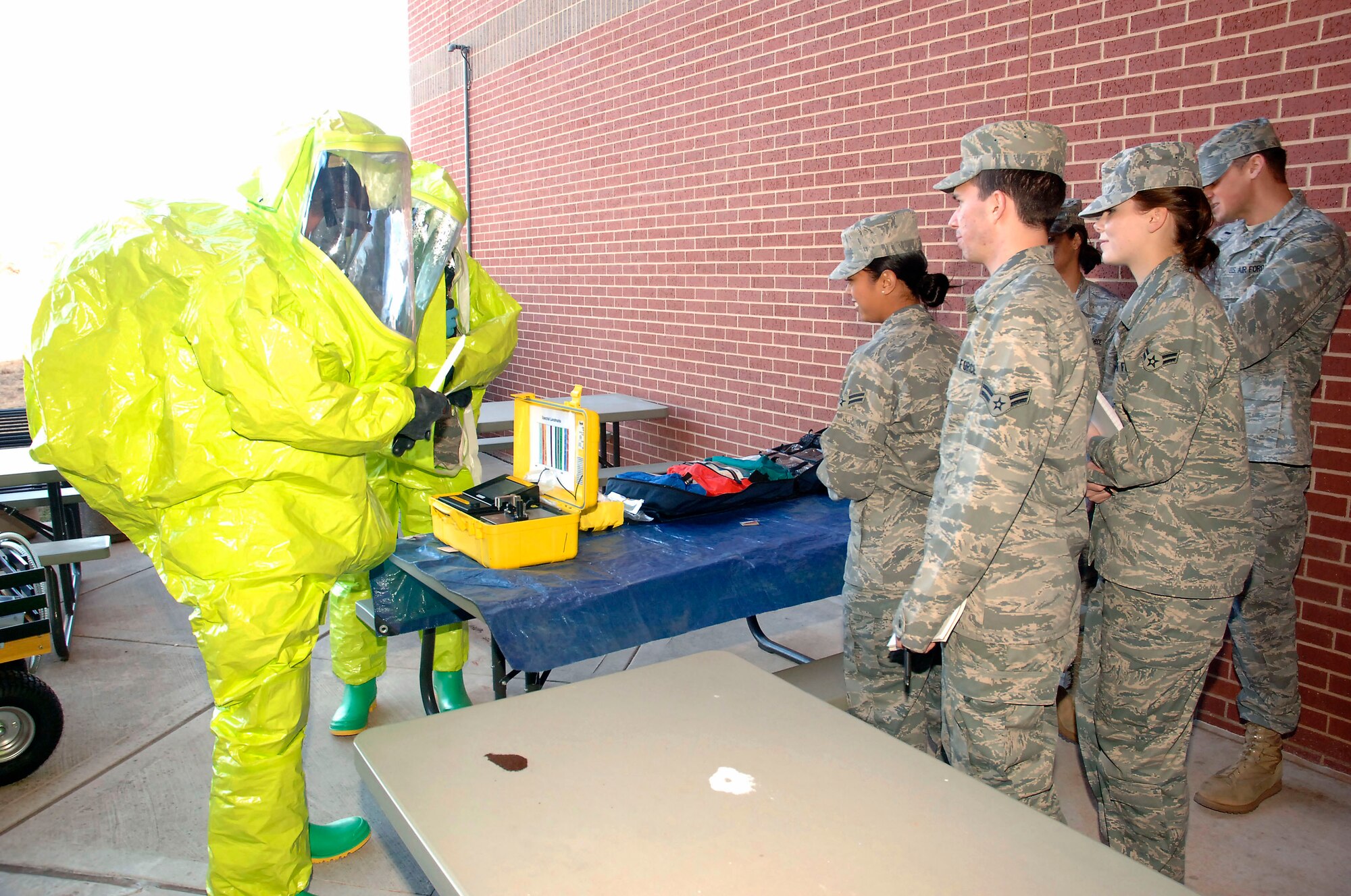 The 72nd Civil Engineer Group emergency management team and the Bio-engineering team recently held a joint training exercise where the first responders suited up in Level-A suits to handle a  “suspicious white powder.” A first responder carefully handles the potentially harmful substance. The responders tested the air and took samples in the affected area. Airmen look on during a learning opportunity at the afternoon exercise which took place near Bldg. 3334. 16 members participated in the exercise. The teams train together so they will be better equipped to handle a response to a weapon of mass destruction. (Air Force photos/Dave Faytinger) 