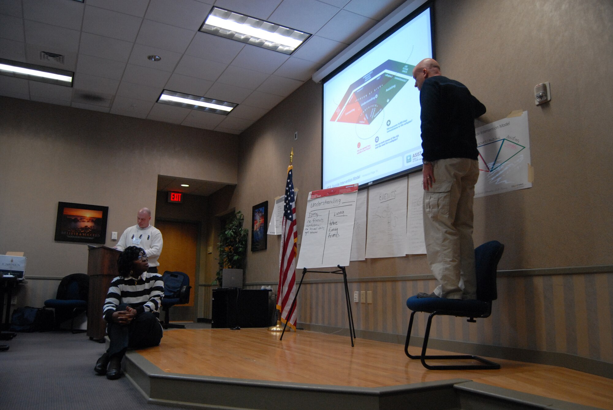 Chaplain (Capt.) Jason Botts (standing) acts as “Ricky,” a suicidal man about to jump off of a bridge at the Applied Suicide Intervention Skills Training held Jan. 29 and 30 at the Airmen & Family Readiness Center. Class participants took turns using their new ASIST learnings to approach “Ricky” in order to assuage his fears and persuade him to step down from the bridge. (U.S. Air Force Photo by Emily Farrington-Smith)