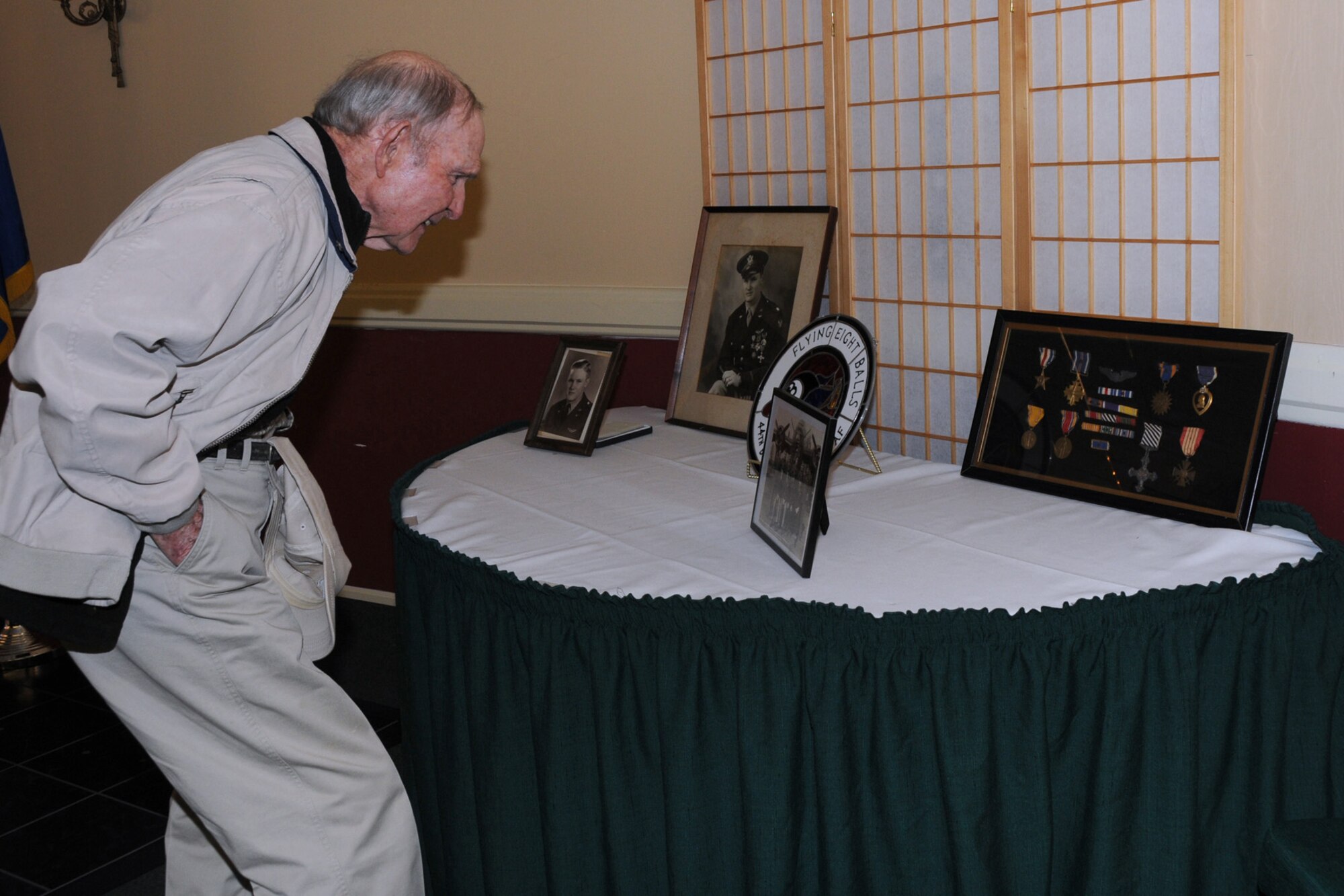 BARKSDALE AIR FORCE BASE, La. – A friend of Walter Holmes looks at some of the photos and decorations of Holmes. Holmes received the Distinguished Service Cross Monday, two days before his 90th birthday and 65 years after the Ploesti Oil Refinery raid where he was a lead pilot in a formation of B-24 Liberators. The raid was conducted on Aug. 1, 1943. (U.S. Air Force photo by TSgt. M. Erick Reynolds)