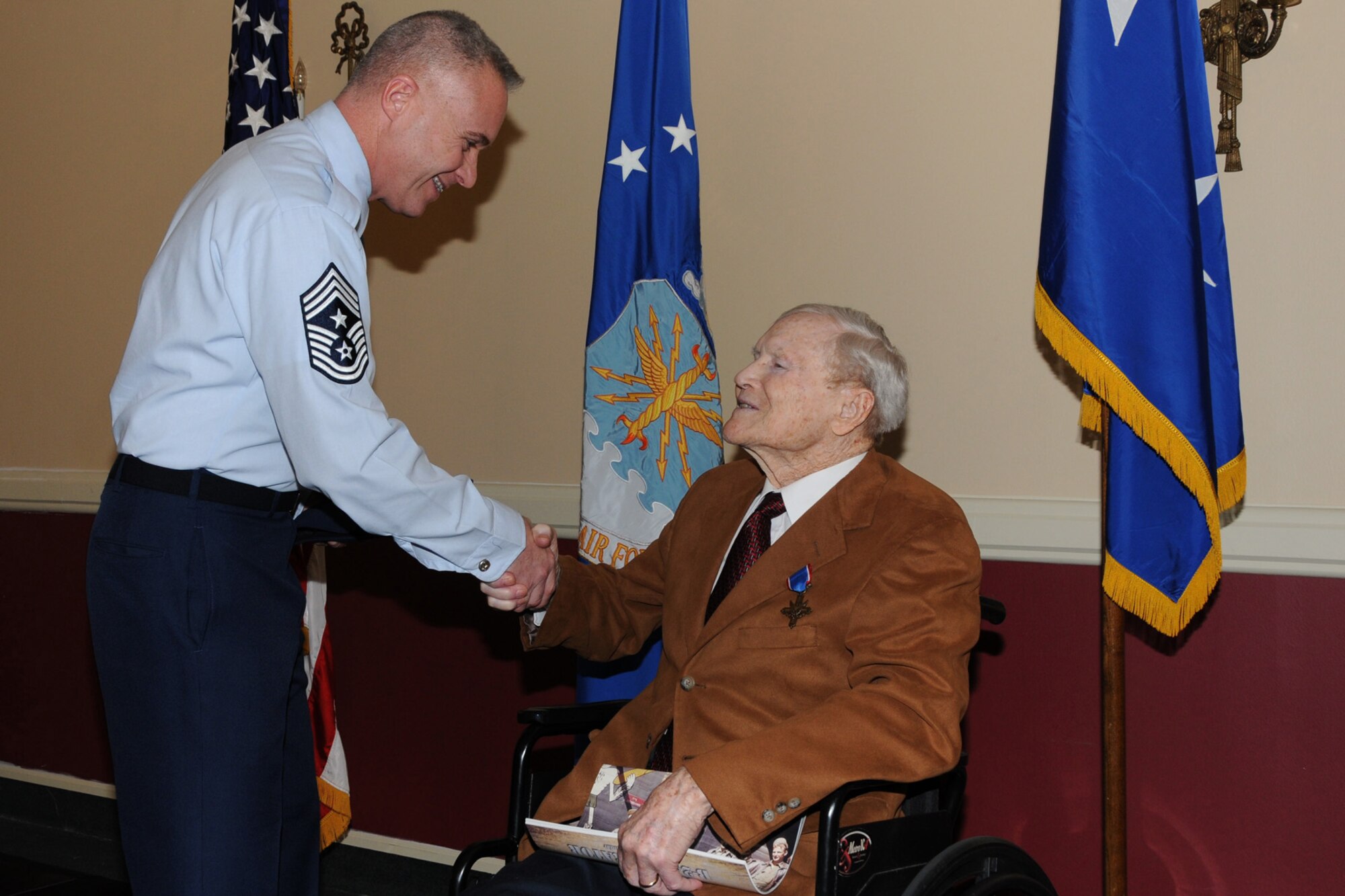 BARKSDALE AIR FORCE BASE, La. – Walter Holmes receives an Eighth Air Force Command Chief coin from Chief Master Sgt. Todd Kabalan, command Chief Master Sgt., 8th  Air Force (Air Forces Strategic). Holmes received the Distinguished Service Cross Monday, two days before his 90th birthday and 65 years after the Ploesti Oil Refinery raid where he was a lead pilot in a formation of B-24 Liberators. The raid was conducted on Aug. 1, 1943. (U.S. Air Force photo by M. Erick Reynolds)