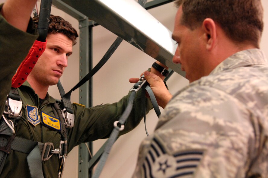 HICKAM AFB - Los Gatos, Calif. native Maj Will Martin, a pilot with the 535th Airlift Squadron, 15th Airlift Wing listens as 15th Airlift Wing Survival Evasion Resistance Escape (SERE) Instructor, Tech Sgt. Sherwood Brown of Muscatine, Iowa provides guidance on the correct way to fasten his parachute while in the harness during a virtual refresher parachute training class on Jan 24, 2009 at Hickam Air Force Base, Hawaii. (U.S.  Air Force photo/Tech Sgt. Cohen A. Young) 