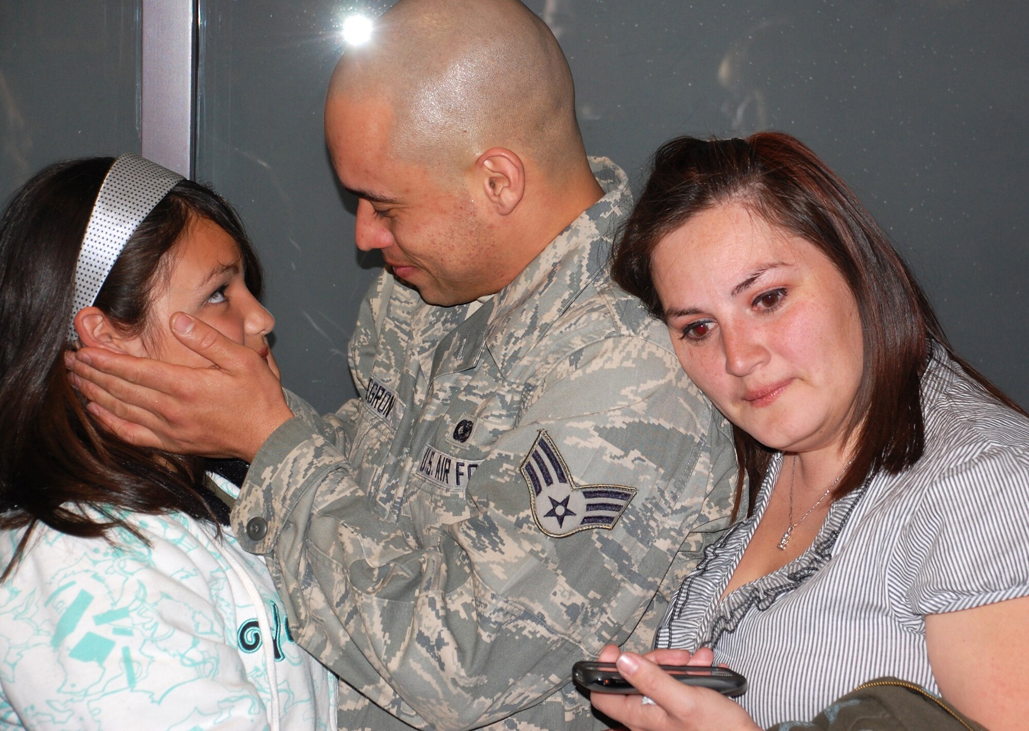 Senior Airman Miguel Negron grasps the face of his daughter Sapphire while wife Mandy embraces him Feb. 5, 2009, after he returned from a six-month deployment at Kirkuk Regional Air Base, Iraq. Airman Negron was one of more than 35 Air Force Reserve security forces Airmen deployed from the 302nd Security Forces Squadron at Peterson Air Force Base, Colo., who returned home to Colorado Springs after supporting Operation Iraqi Freedom. "I can't wait to barbeque with my family again, even if it's 20 degrees outside," an excited Airman Negron said. "But I'm also ready to get back to snowboarding." (U.S. Air Force photo/Tech. Sgt. Daniel Butterfield)