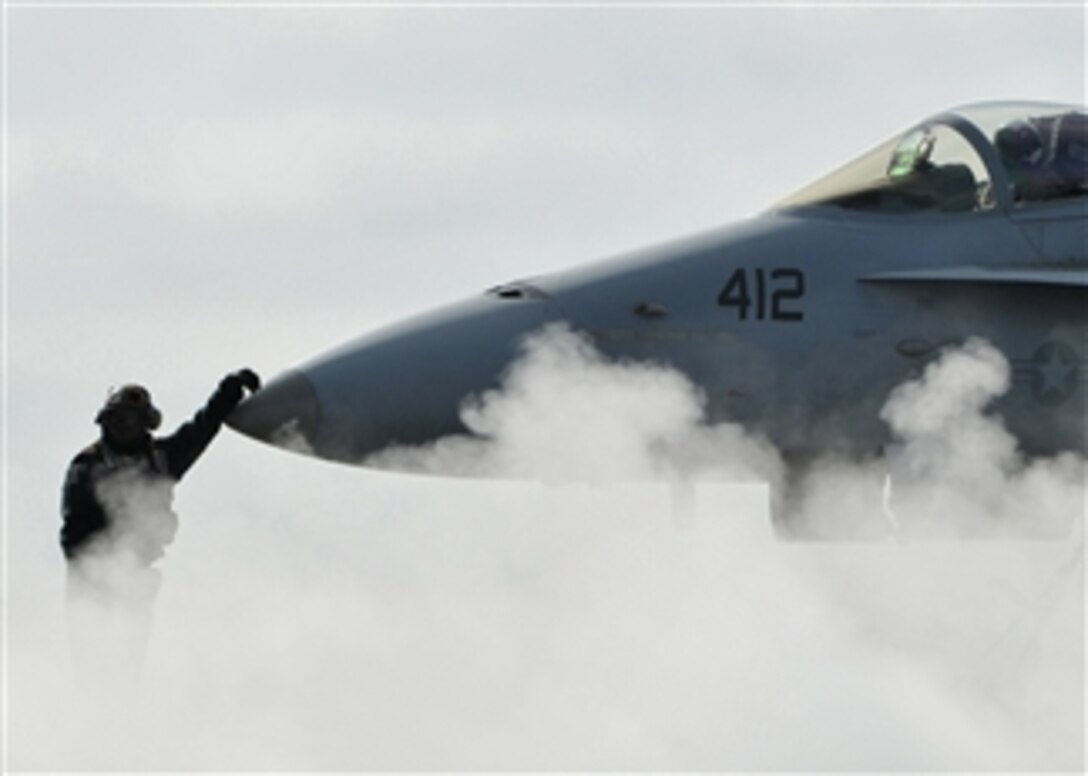 U.S. Navy Petty Officer 3rd Class Bashab Biswas, assigned to Strike Fighter Squadron 34, waits with an F/A-18C Hornet aircraft before it is launched from the flight deck of the aircraft carrier USS Abraham Lincoln (CVN 72) while the ship is underway conducting training in the Pacific Ocean on Jan. 31, 2009.  