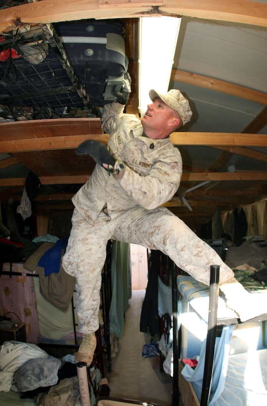 Gunnery Sgt. Trent Narra, the company gunny and assistant camp commandant for Camp Korean Village, Iraq searches through the rafters of contractors’ living quarters during a health and comfort inspection Feb. 7.  One of Narra’s primary responsibilities is to ensure the safety of the U.S. service members aboard the base. (Official USMC photo by Capt. Paul L. Greenberg)