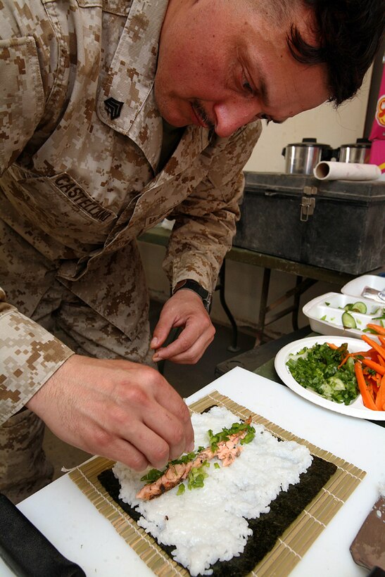 Sergeant Alejandro Castellano, the utilities maintenance chief for 1st Civil Engineering Battalion, Regimental Combat Team 8, garnishes a salmon-filled sushi wrap with freshly cut vegetables at the regimental field mess, here. Castellano has been cooking since he was nine-years-old. (Official Marine Corps photo by Cpl. Eric C. Schwartz)