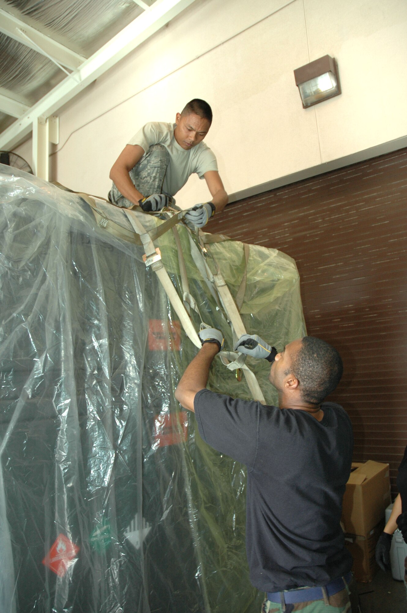Tech. Sgt. Andrew Sana (top) and Tech. Sgt. Dedric Brown, 624th Civil
Engineer Squadron, fasten a net on top of a pallet loaded with CE support
equipment.  624th CES is participating in an Operational Readiness
Inspection which kicked off Feb. 5 at Hickam Air Force Base, Hawaii. 
