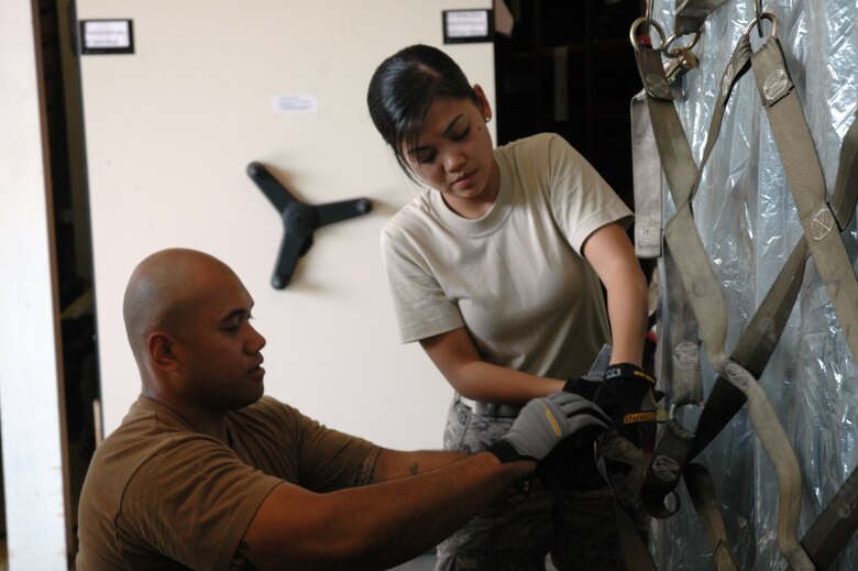 Staff Sgt. Isaia Ahkiong helps Airman First Class Kathrina Domingo attach
the cargo netting to the equipment pallet. Both Airmen are part of the
624th Civil Engineer Squadron "pallet team" supporting the Operational
Readiness Inspection at Hickam Air Force Base that kicked off Feb. 5. (Air Force photo/Capt. Christy Stravolo)
